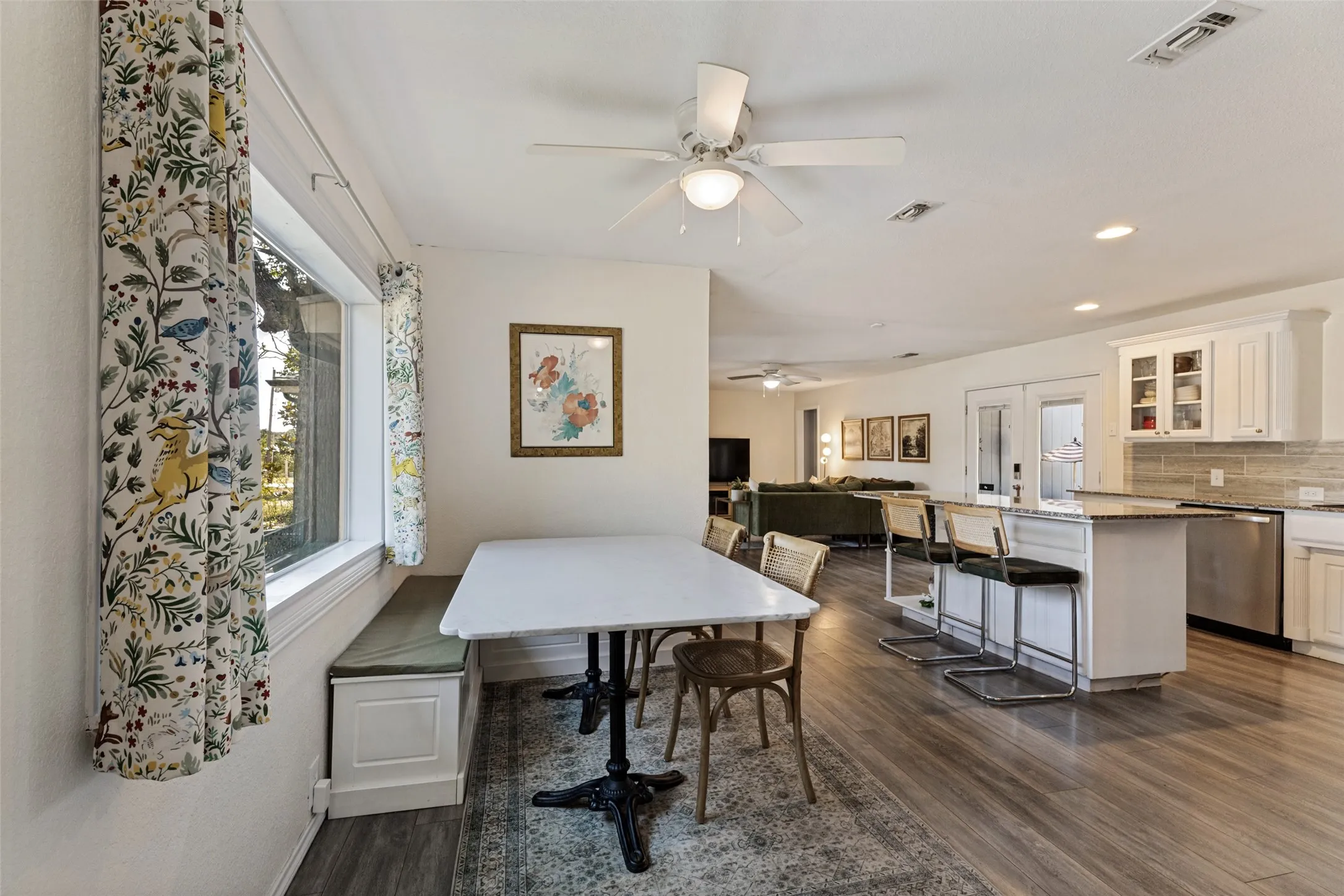 Open-concept living space featuring wood-finish flooring, a built-in window bench, a ceiling fan, and recessed lighting