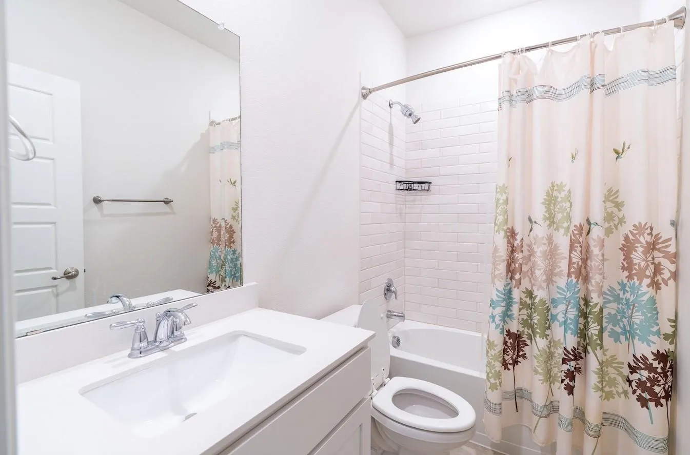 Bathroom featuring a single vanity with an integrated sink, polished chrome faucet, and a subway tile shower surround