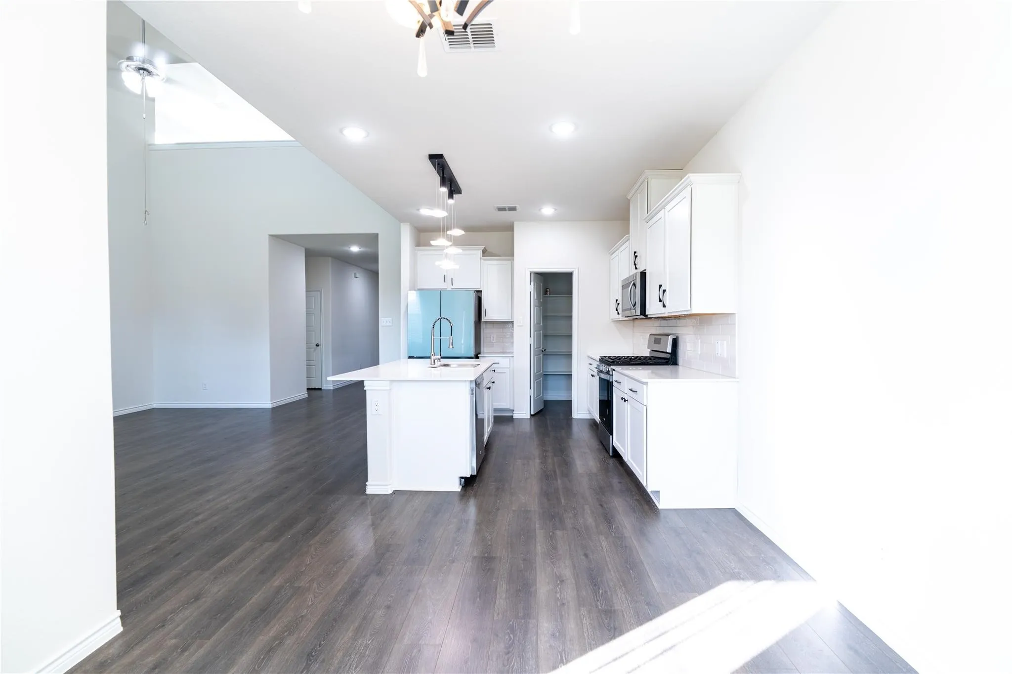 Kitchen with white cabinetry, stainless steel appliances, and a central island with a sink
