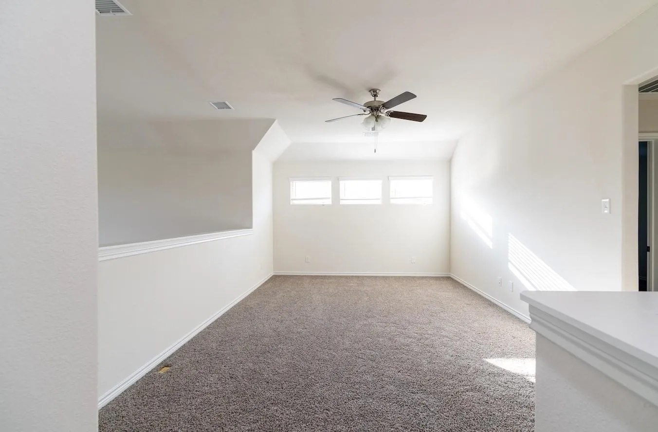 Carpeted room featuring a ceiling fan, three horizontal windows with blinds, and white painted walls