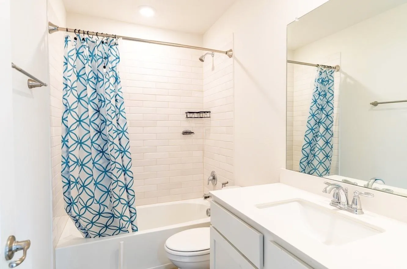 Bathtub with subway tile surround, polished chrome fixtures, integrated sink vanity with a white countertop, and a large wall-mounted mirror