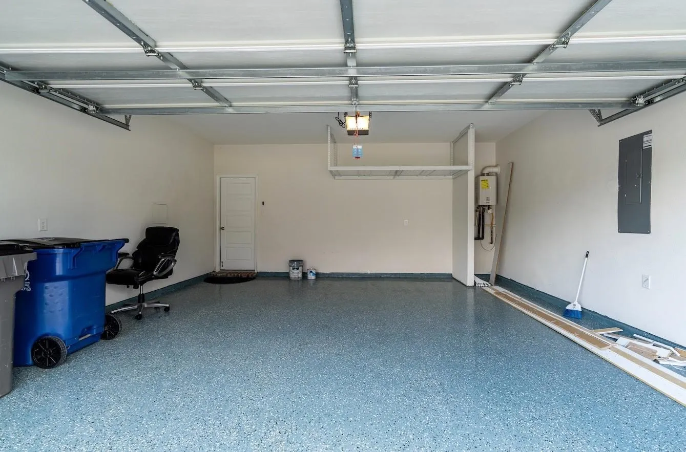 Epoxy-coated flooring, overhead garage door, built-in elevated storage shelf, interior access door, wall-mounted utility panel