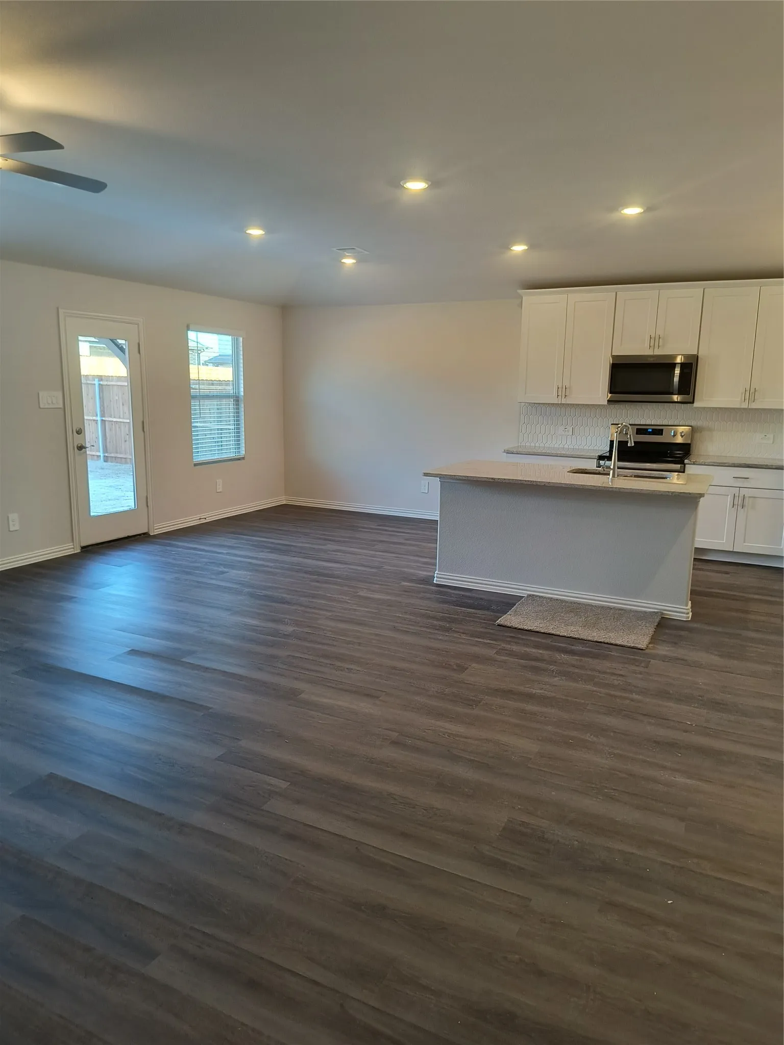 Open-concept living space with wood-finish flooring, recessed lighting, and a ceiling fan