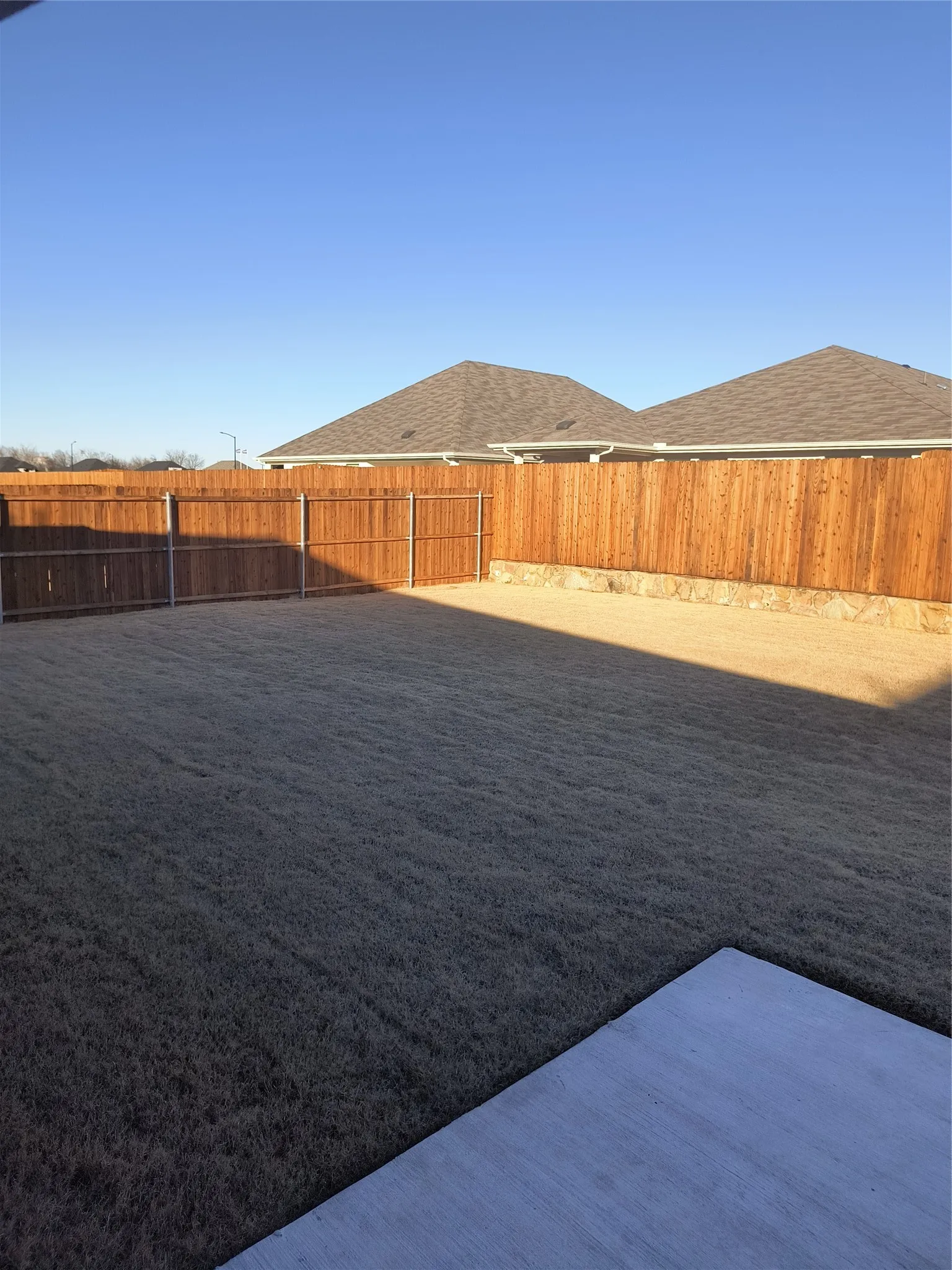 Expansive backyard featuring a privacy fence, manicured lawn, and a concrete patio