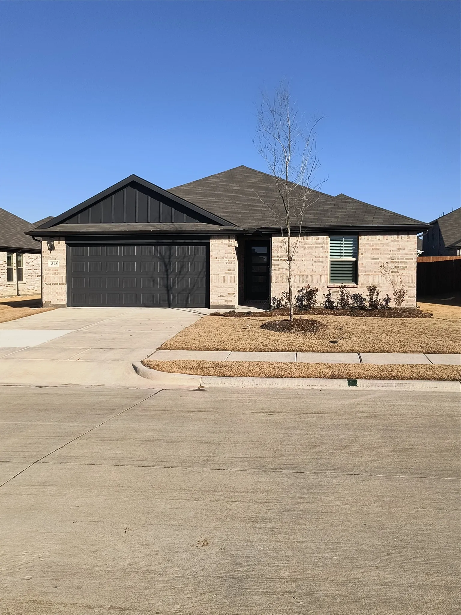 Brick and panel siding exterior, attached garage, concrete driveway, and front landscaping