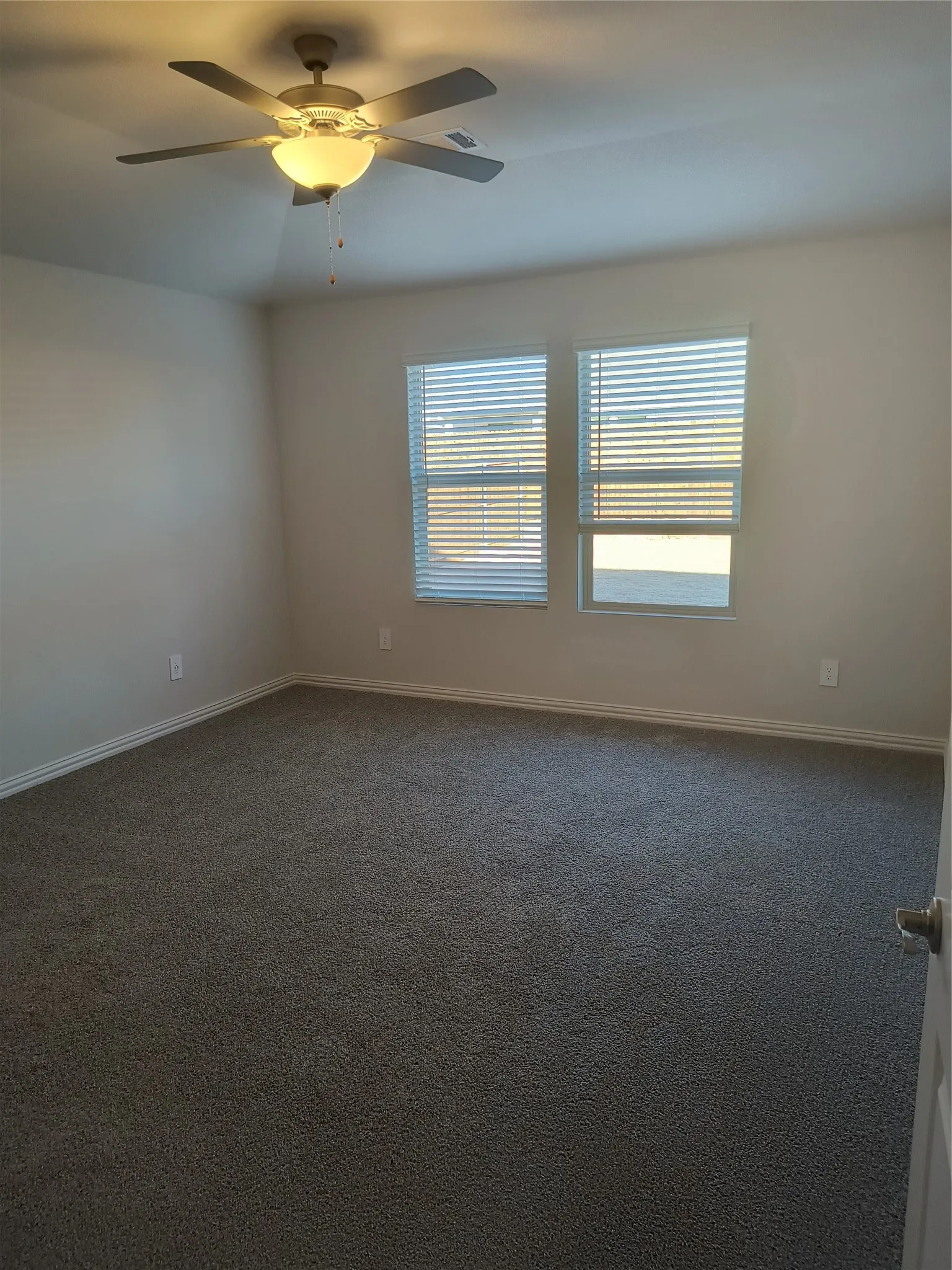 Recessed ceiling fan with integrated lighting, two windows with blinds, and gray carpet flooring