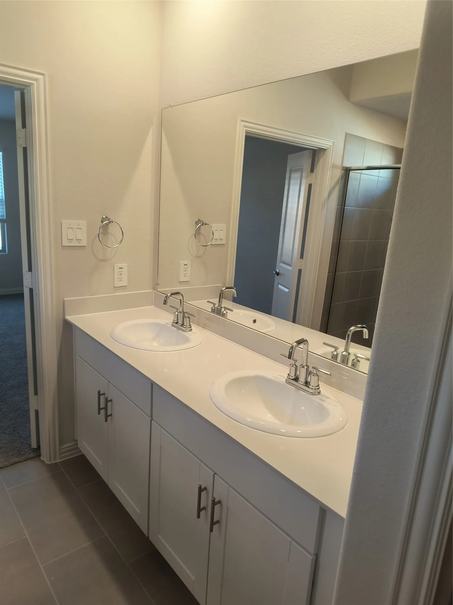 Dual vanity with white cabinetry, integrated sinks, chrome fixtures, and a large wall-mounted mirror