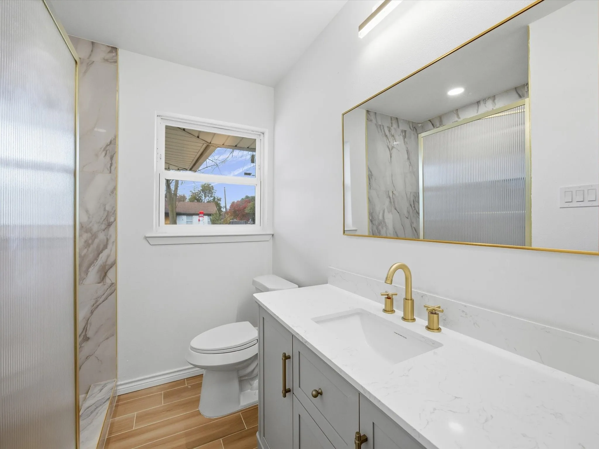 Modern vanity with a light gray finish, brass hardware, and an integrated white sink