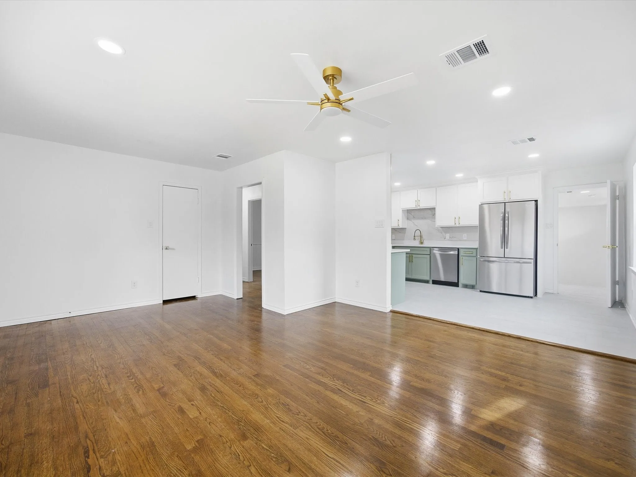 Wood-finish flooring, recessed lighting, and a ceiling fan in the living area