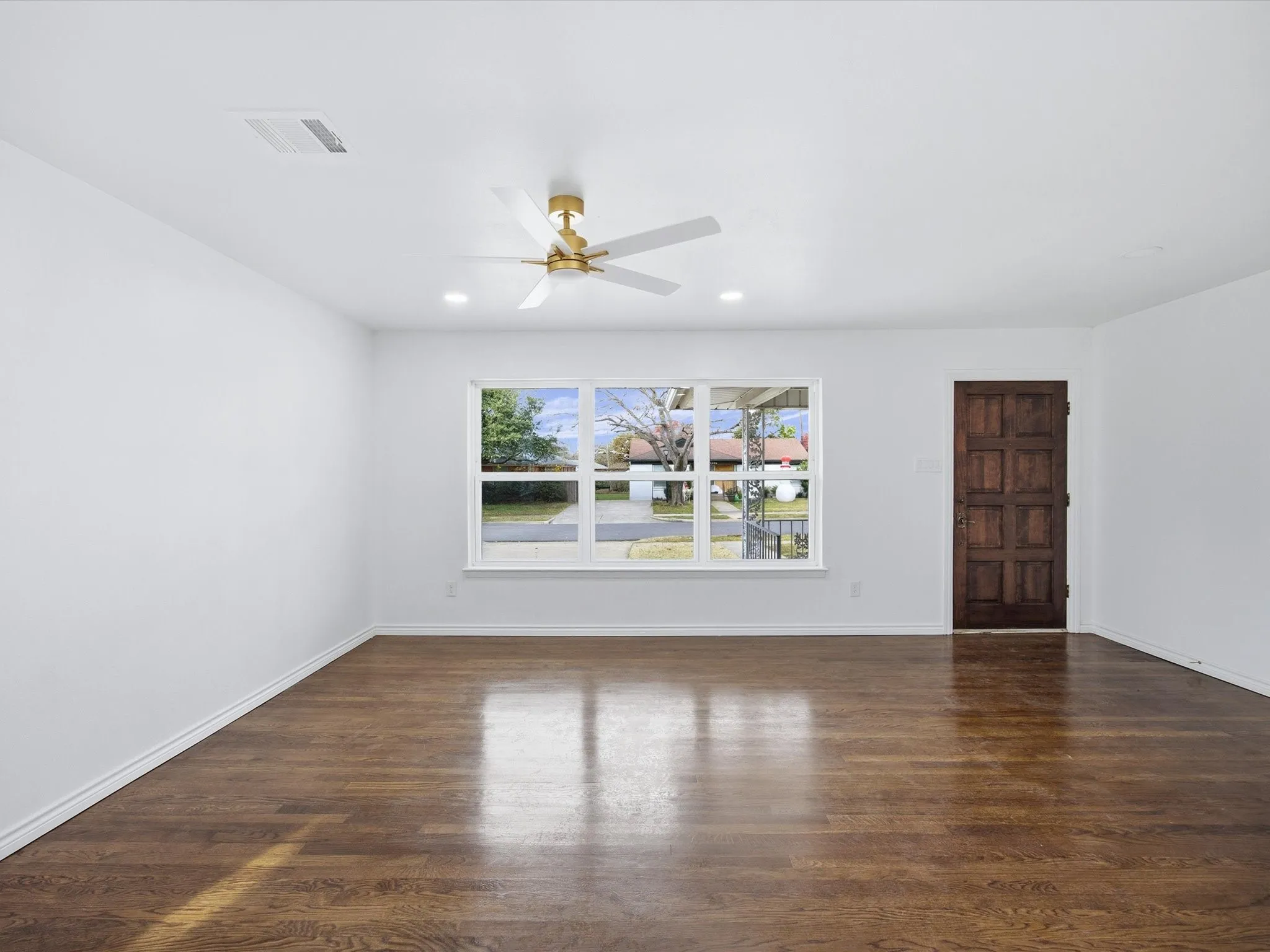 Hardwood flooring, recessed lighting, white walls, gold-finish ceiling fan, and a paneled entry door