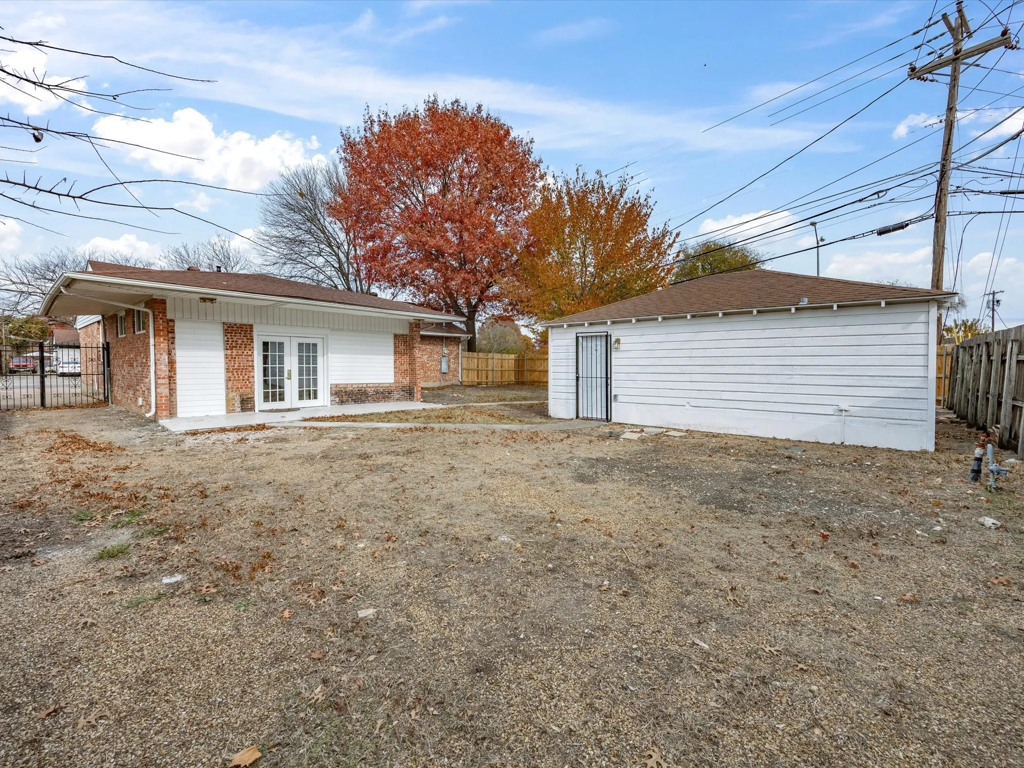 Brick and siding exterior with double French doors, concrete patio, and detached garage