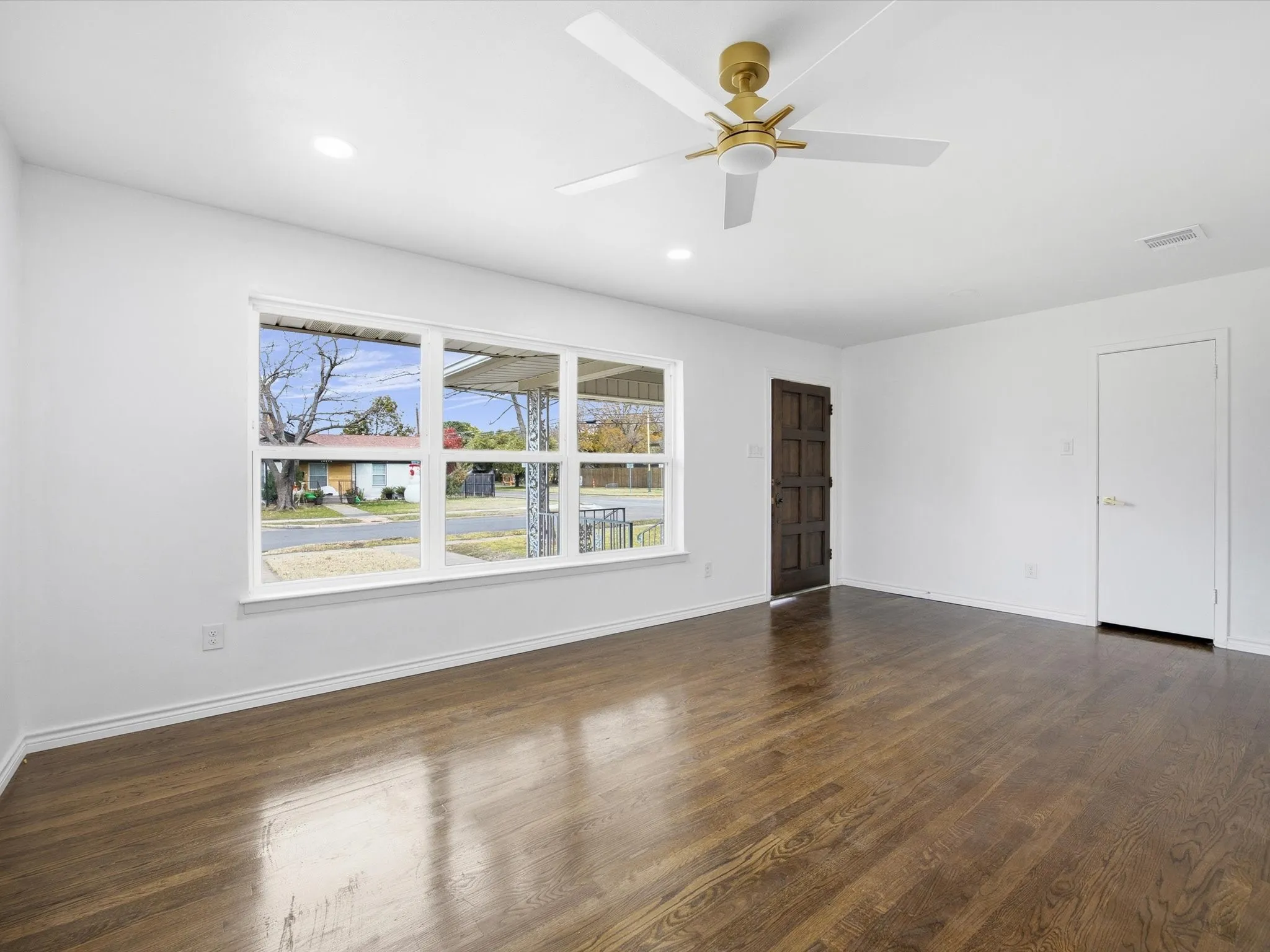 Dark-stained wood-finish flooring, white walls, and a multi-pane window