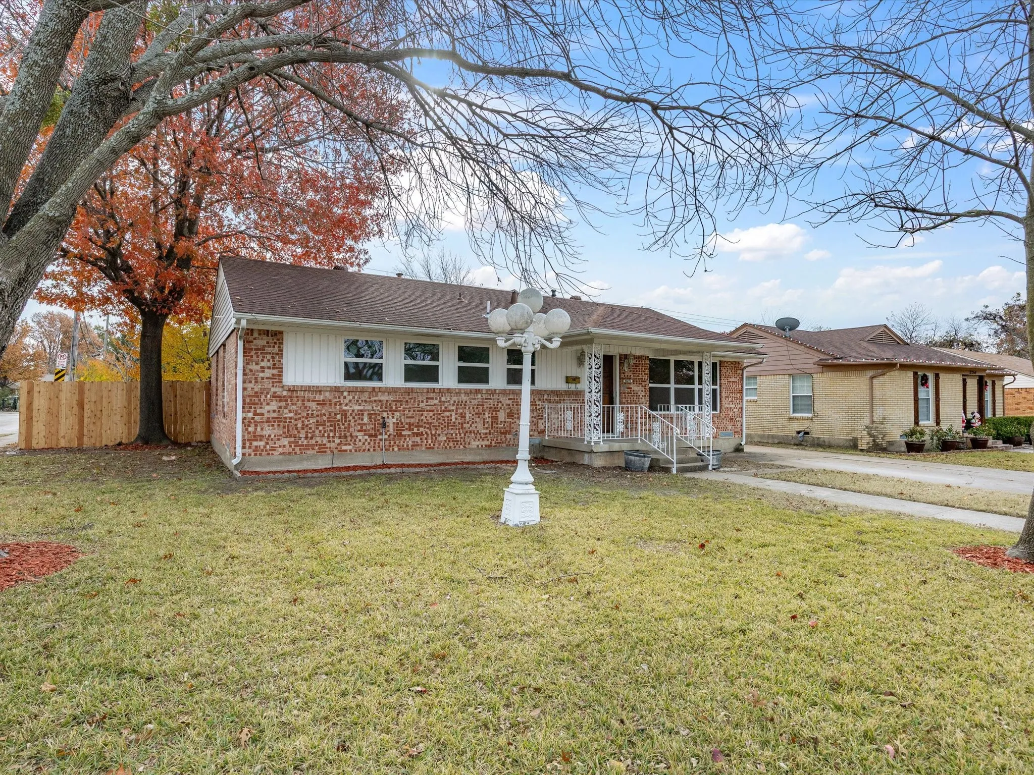 Brick exterior facade, white vinyl siding accents, concrete driveway, and a fenced side yard