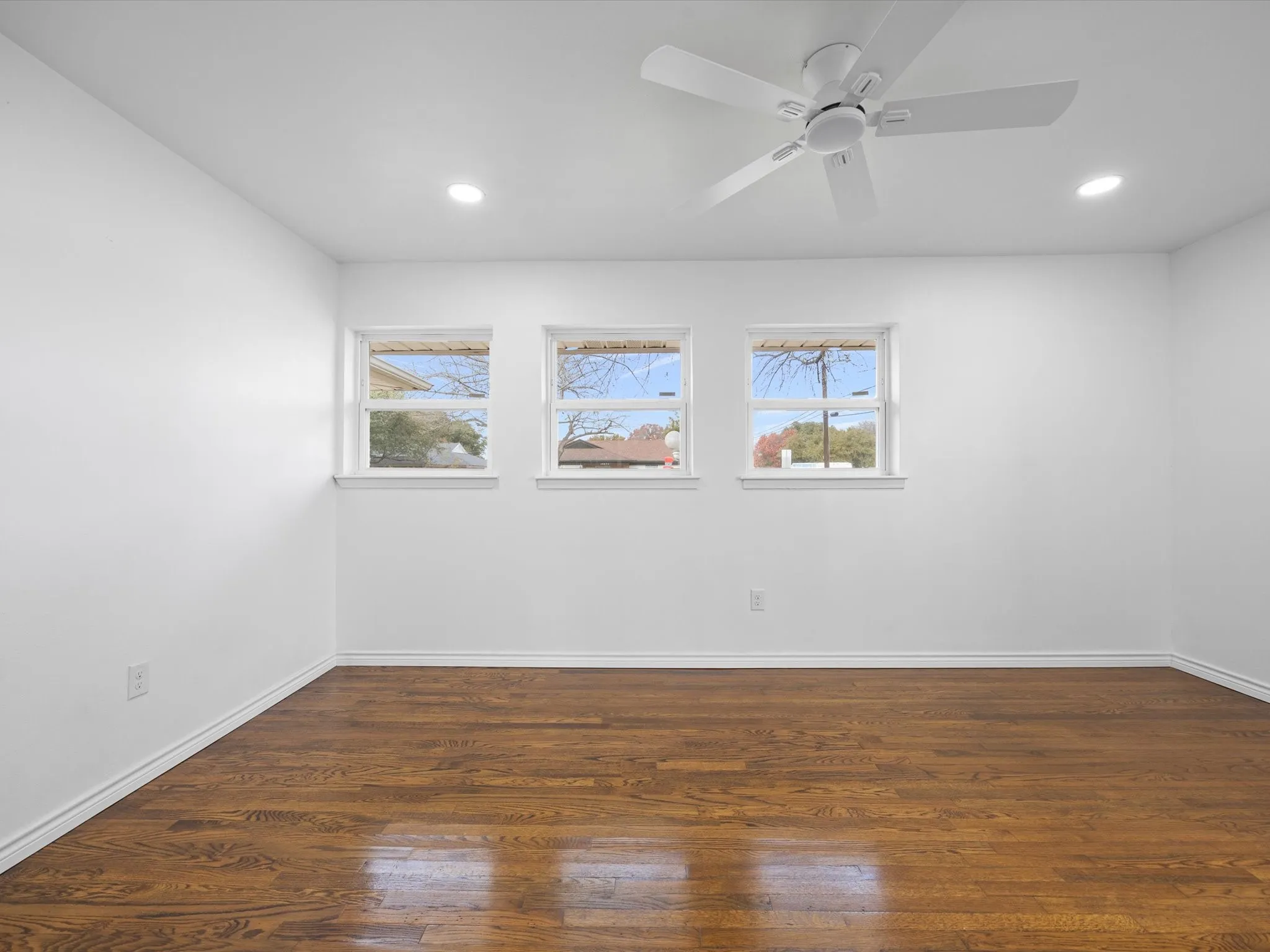 Wood-finish flooring, recessed lighting, ceiling fan, and three windows