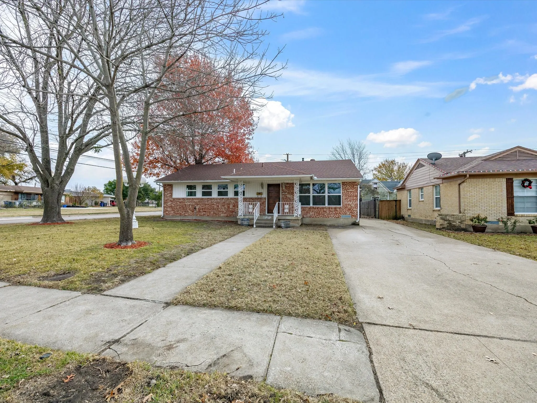 Brick exterior facade with white siding, covered front entry, concrete walkway, and a concrete driveway