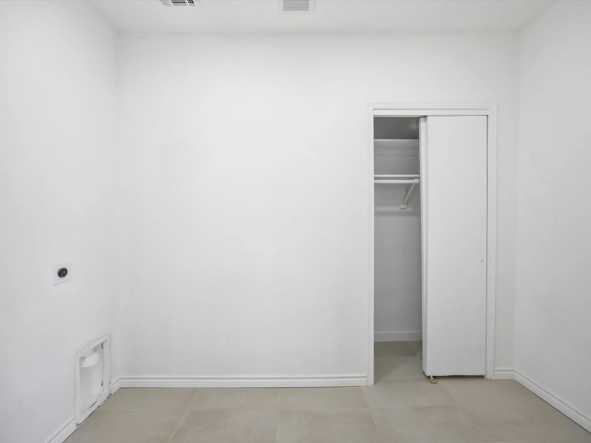 White walls with an integrated closet featuring sliding doors and interior shelving