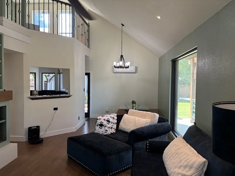 Vaulted ceiling with an open mezzanine, wood flooring, and a large picture window