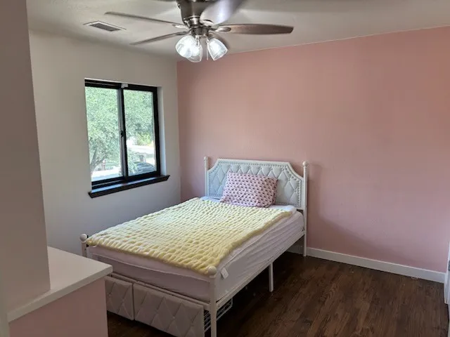 Wood flooring, ceiling fan with integrated lighting, and a window with a dark frame