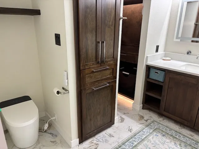White custom vanity with integrated rectangular sink, lots of storage, and polished chrome faucet