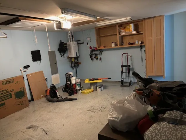Garage with tankless water heater, overhead lighting, and built-in cabinetry for storage