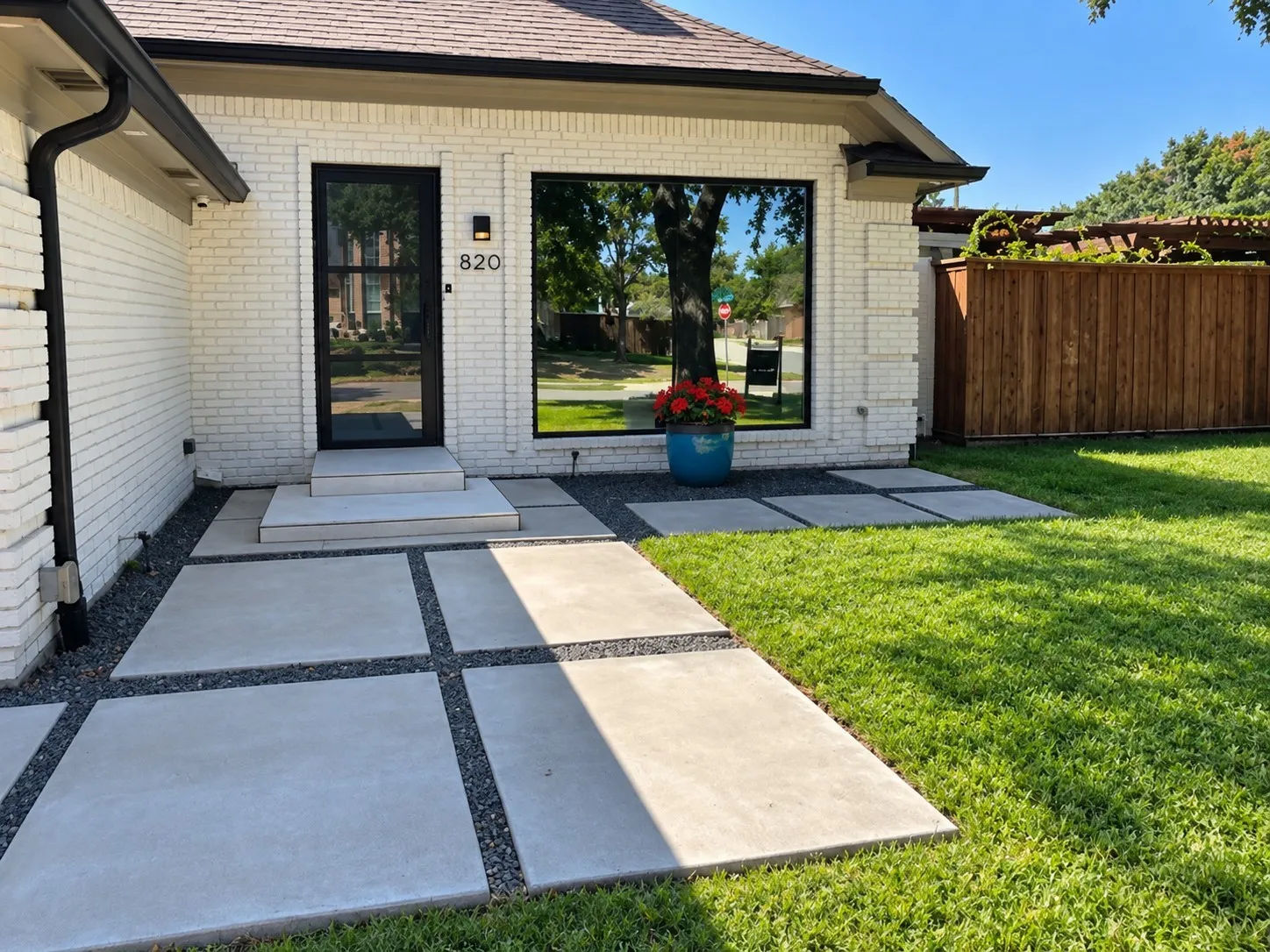 White painted brick exterior with a dark trim roofline welcome to your new home! *AI generated grass and flowers*