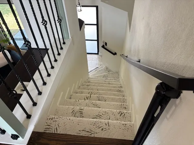 Wrought iron balusters, patterned stair runner, and a contemporary wall-mounted handrail