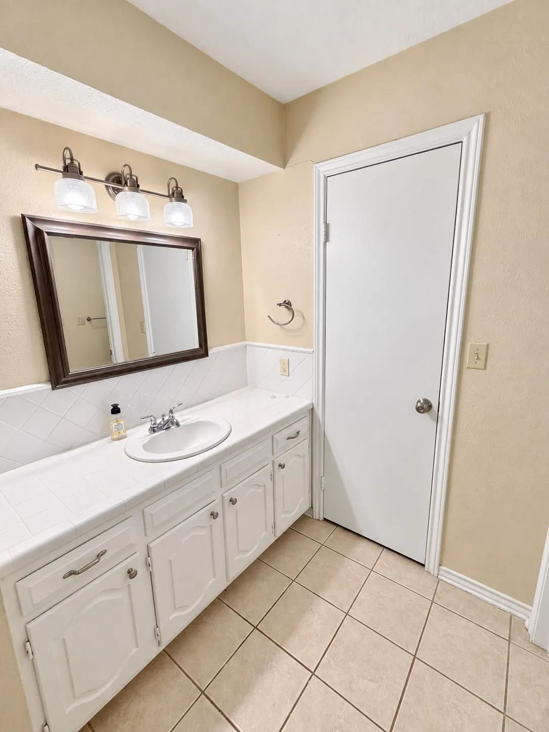 White vanity with ample cabinet storage, integrated sink, and white tiled countertop