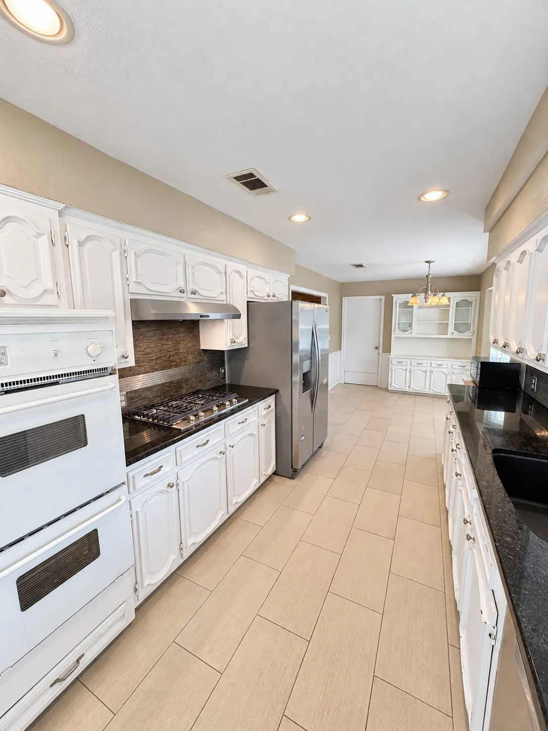 Kitchen featuring white cabinetry, dark countertops, a built-in double oven, and stainless steel appliances