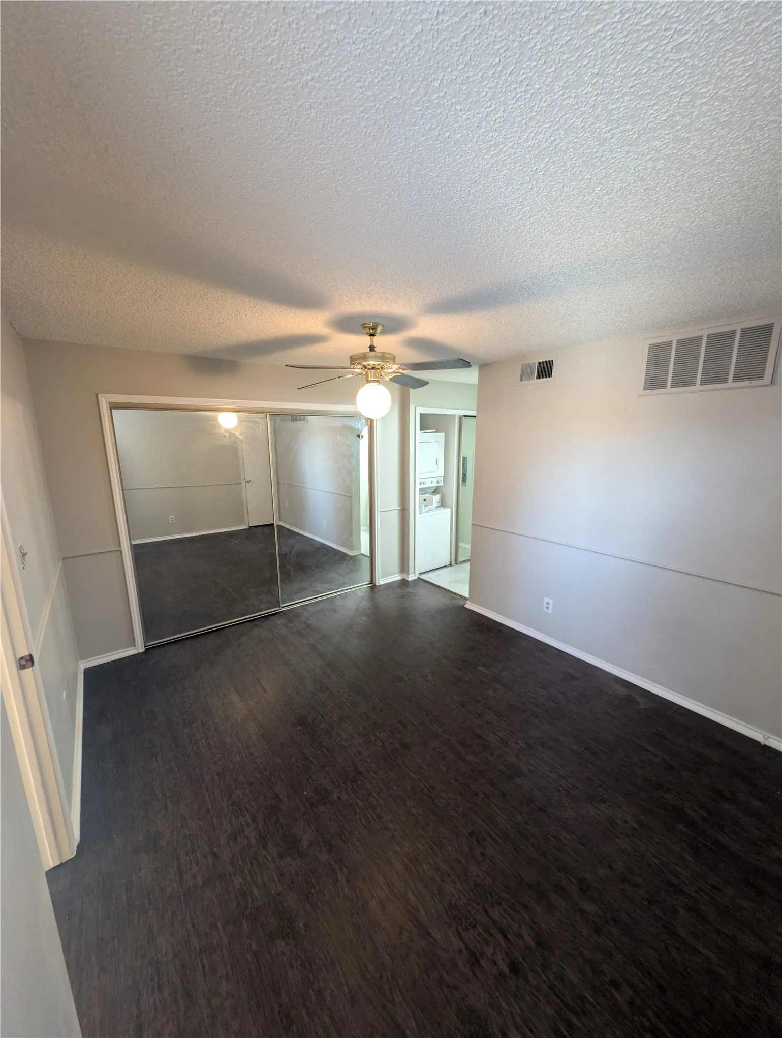 Wood-finish flooring, mirrored sliding closet doors, ceiling fan with integrated lighting, and neutral wall tones