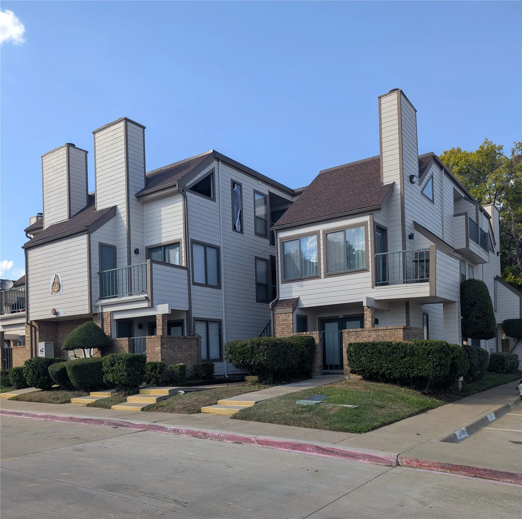Multi-level residences featuring light-colored siding, brick accents, and balconies with metal railings