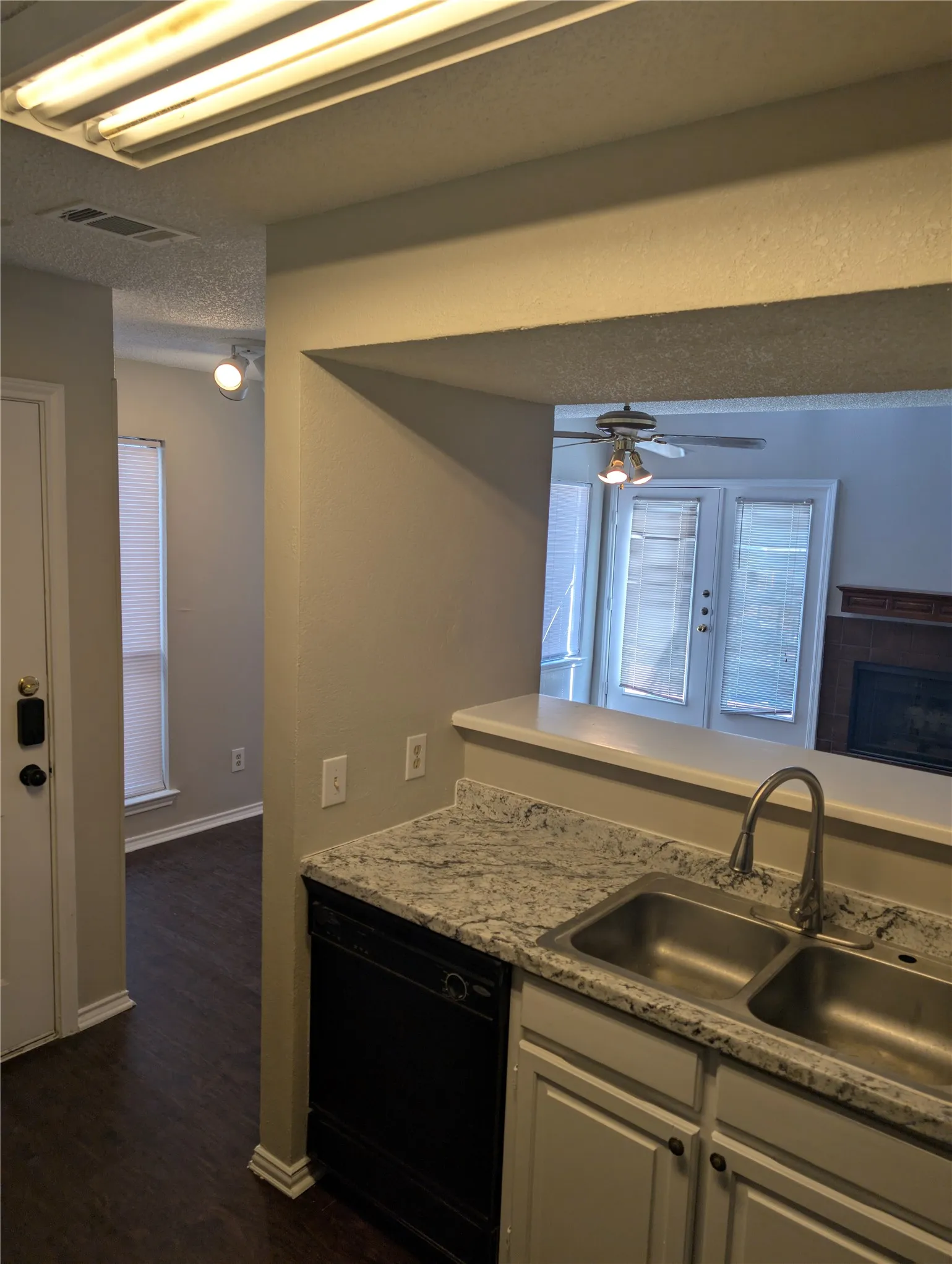 Kitchen featuring a double stainless steel sink, gooseneck faucet, light-toned countertops, and white cabinetry