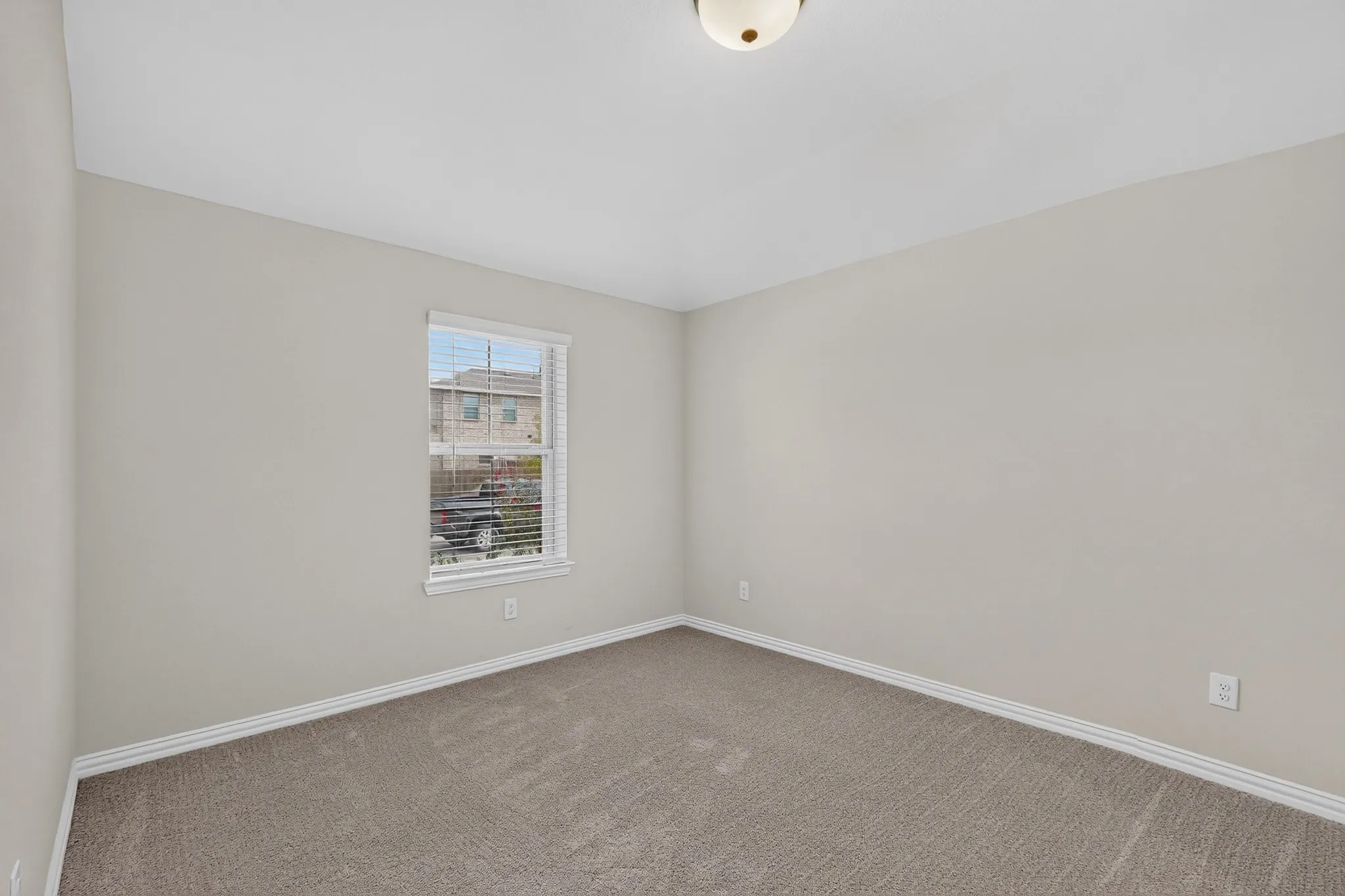 Neutral wall finishes and ceiling, carpeted flooring, and a single window with blinds