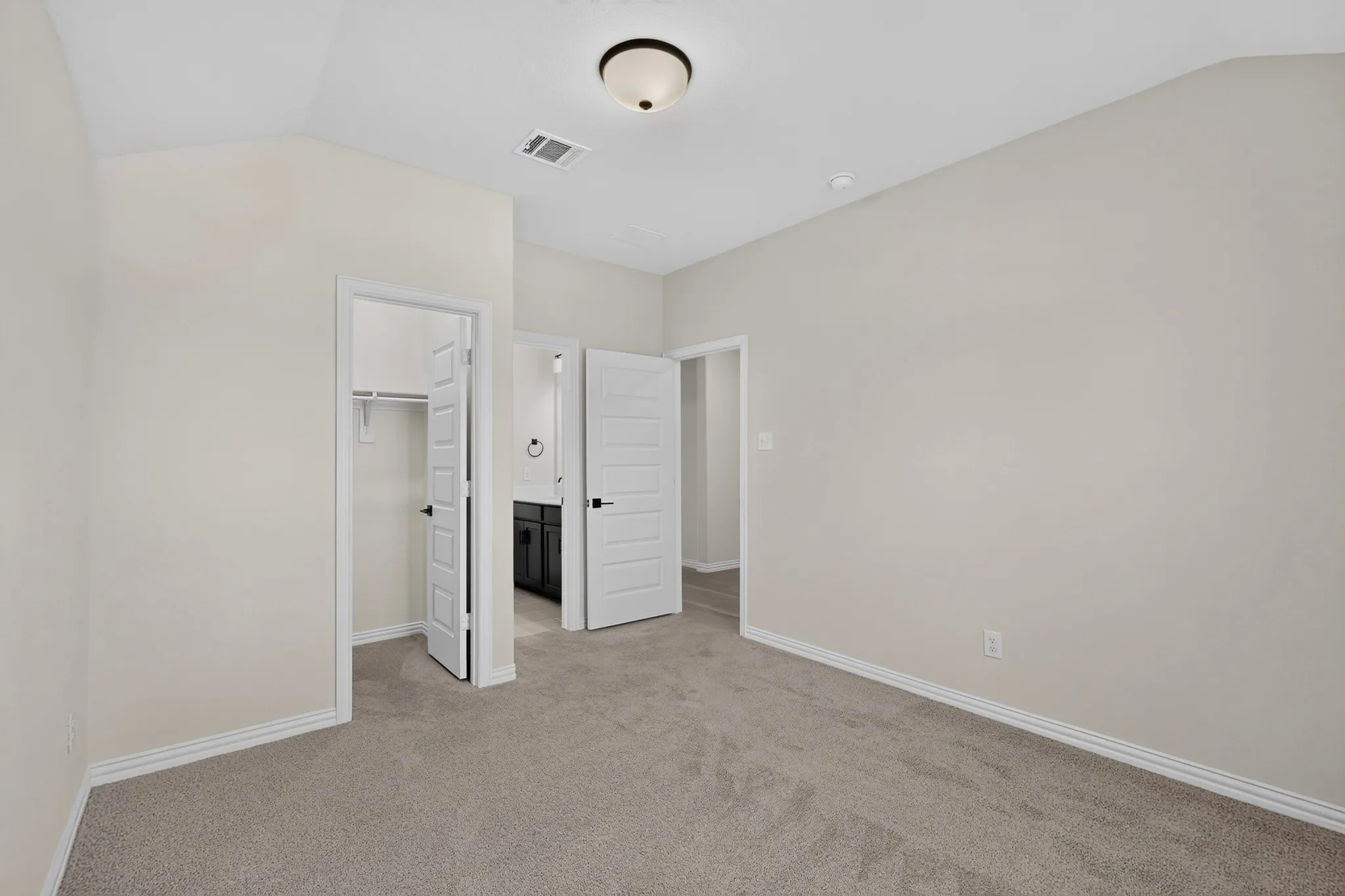 Neutral tone wall paint, plush carpet flooring, white trim, paneled interior doors, and a ceiling-mounted light fixture