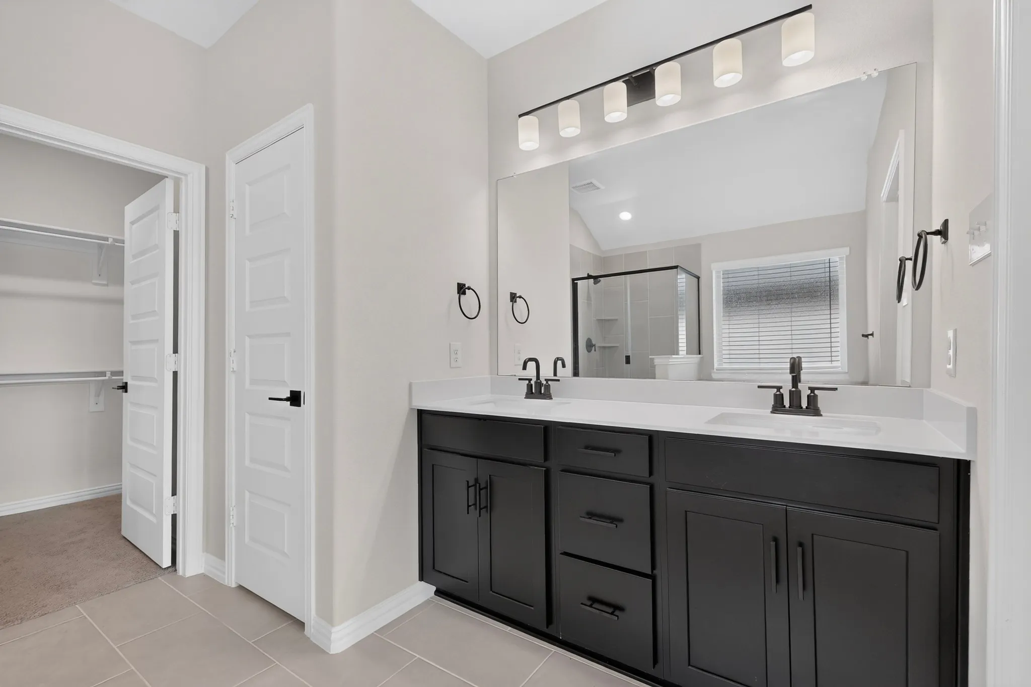 Dual vanity with black cabinetry, white countertops, and matte black fixtures