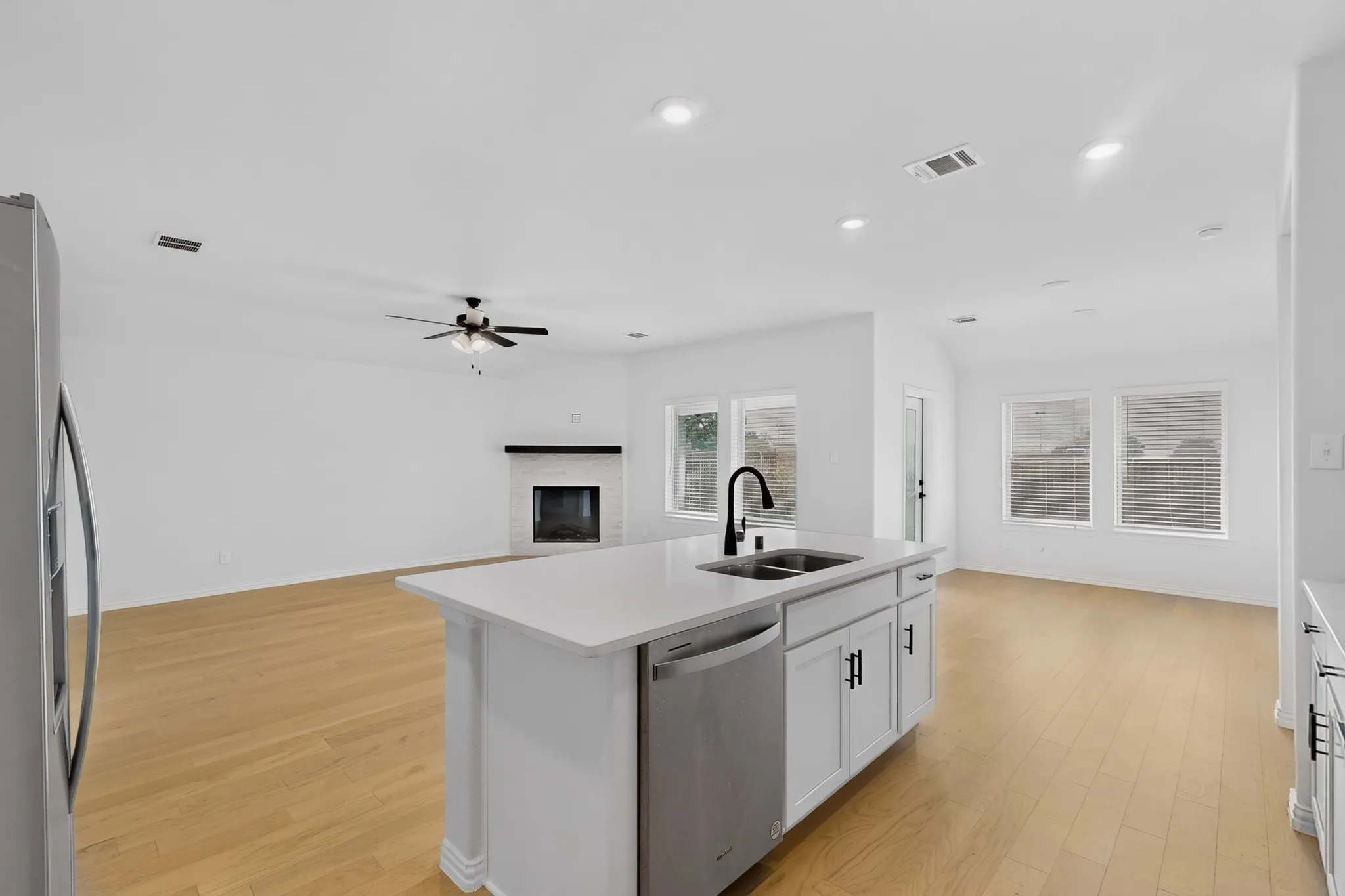 Kitchen island with an undermount sink and matte black faucet, stainless steel dishwasher, and white cabinetry