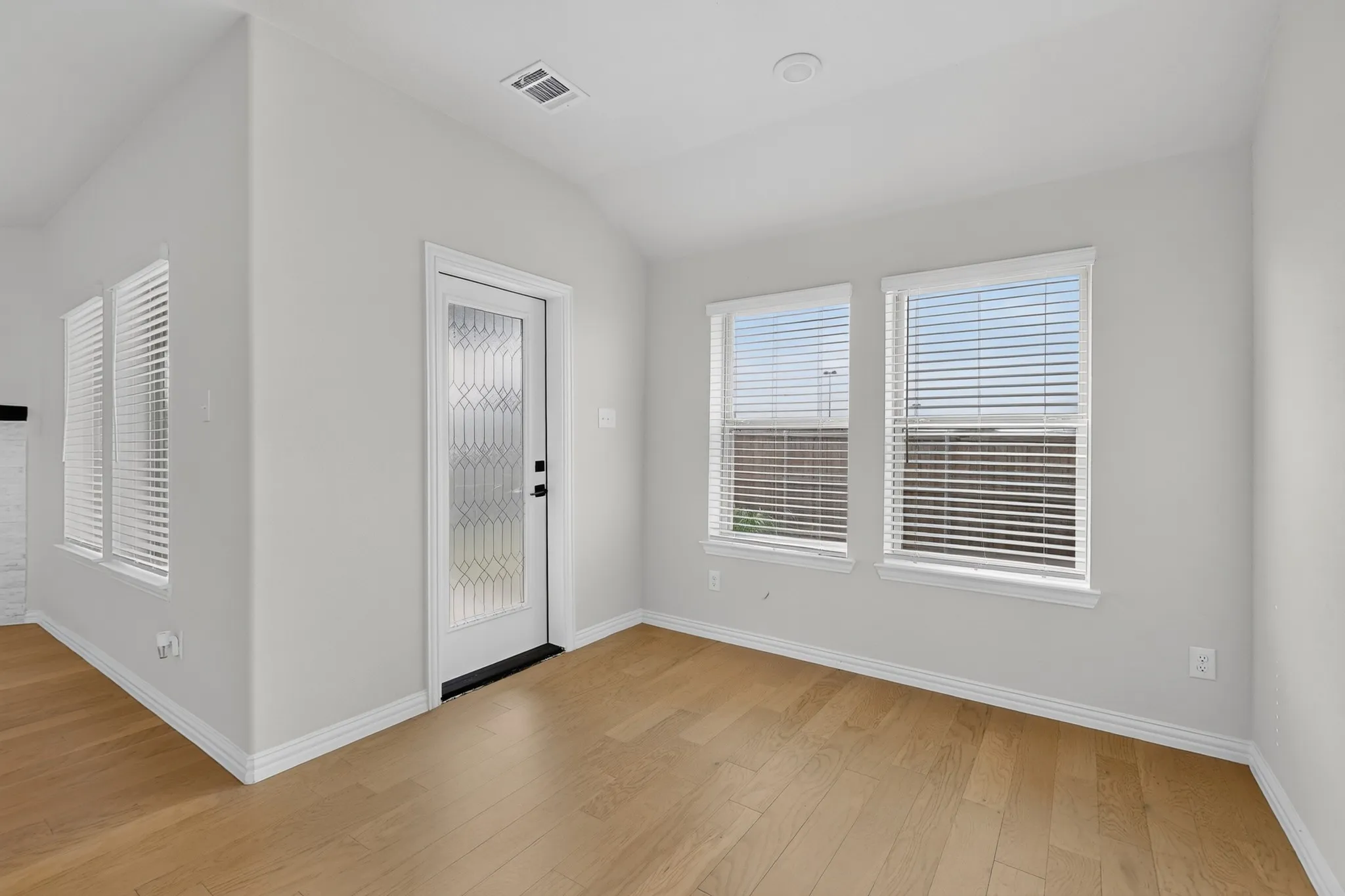 Wood-finish flooring, white trim, recessed lighting, and a decorative glass panel door