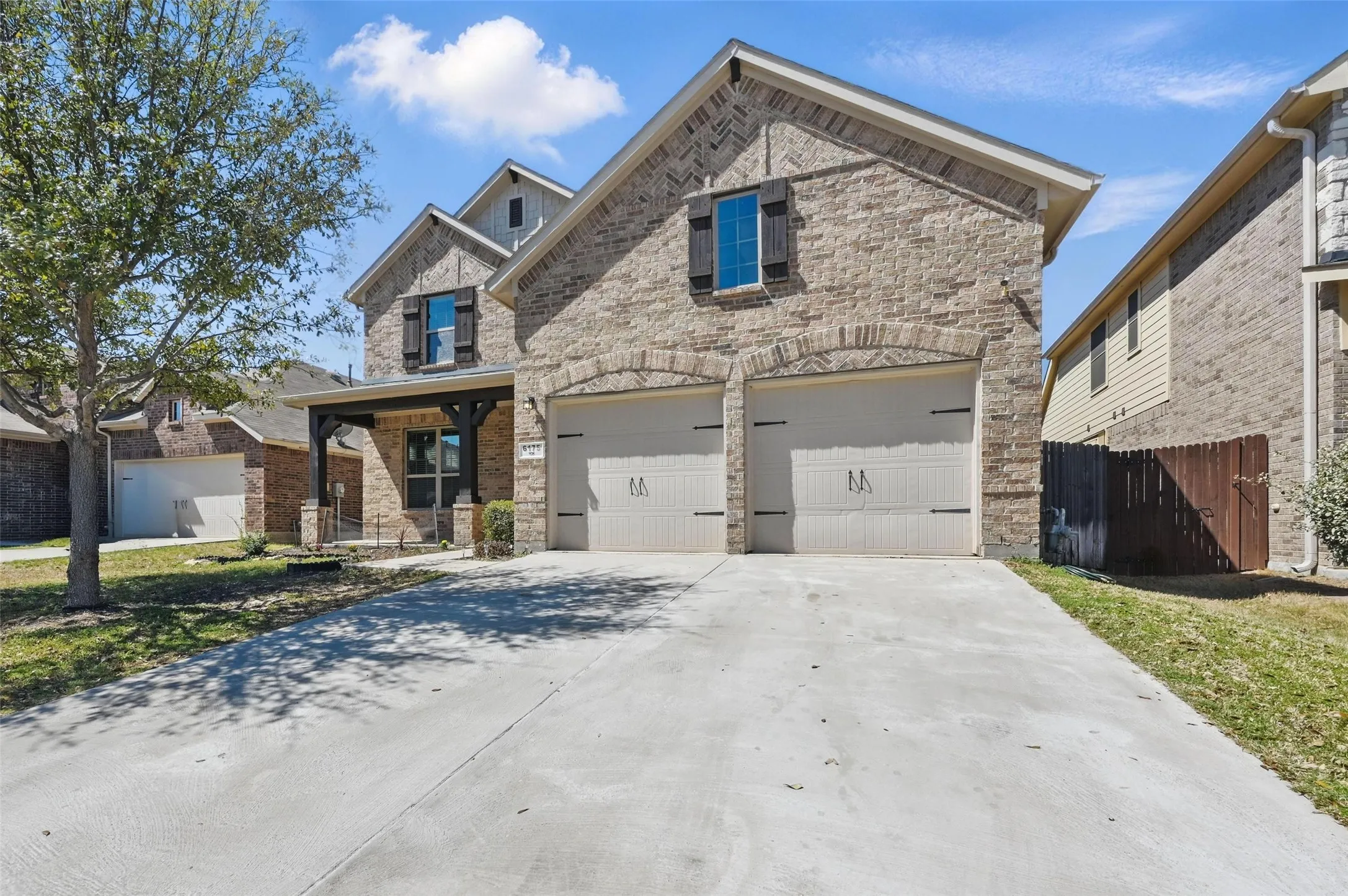Stone veneer exterior with a covered porch entry, two-car garage, and concrete driveway