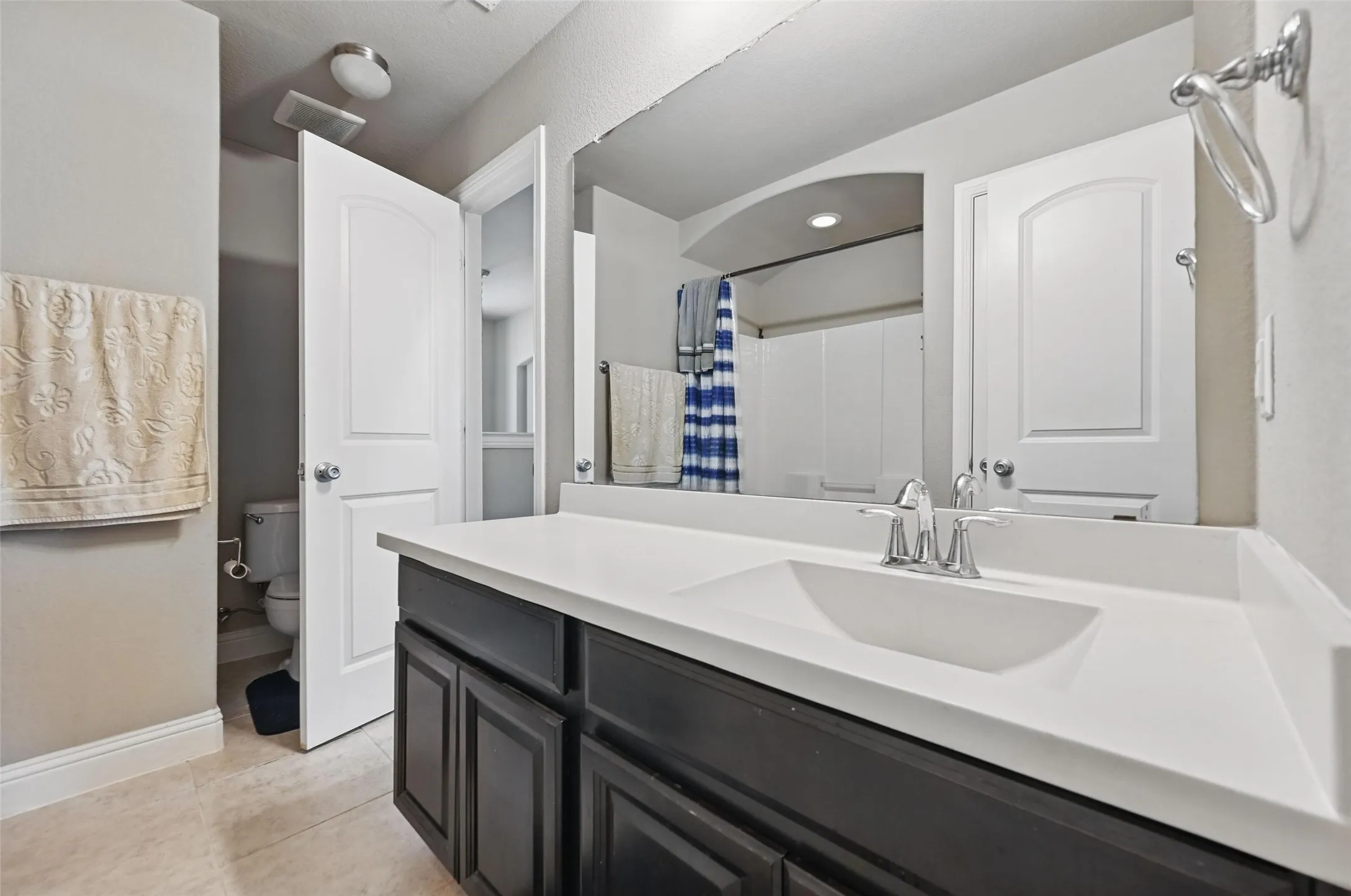 Single vanity with an integrated sink, polished chrome faucet, and dark wood-finish cabinetry