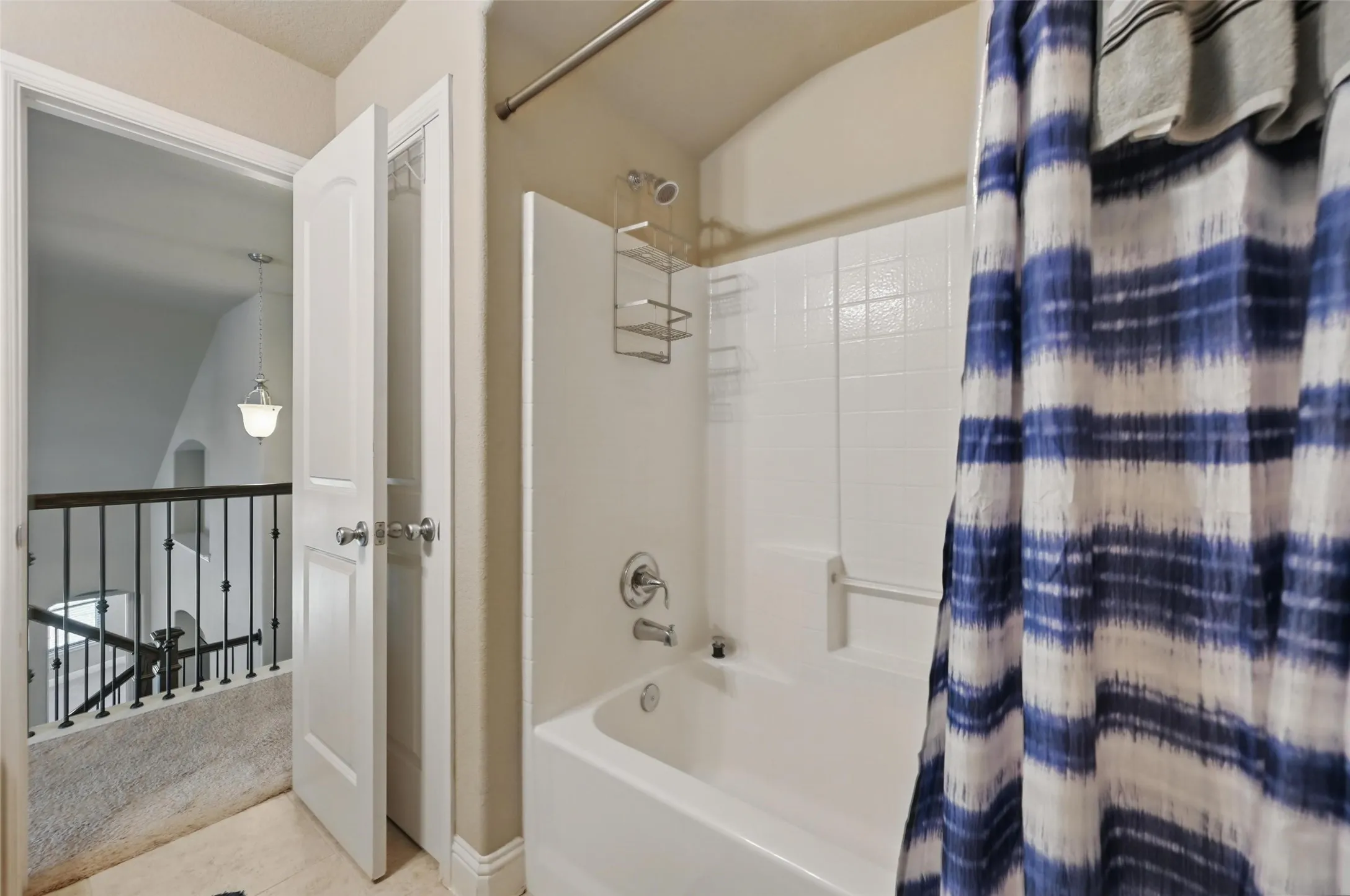 Bathtub with integrated shower, white subway tile surround, and chrome fixtures