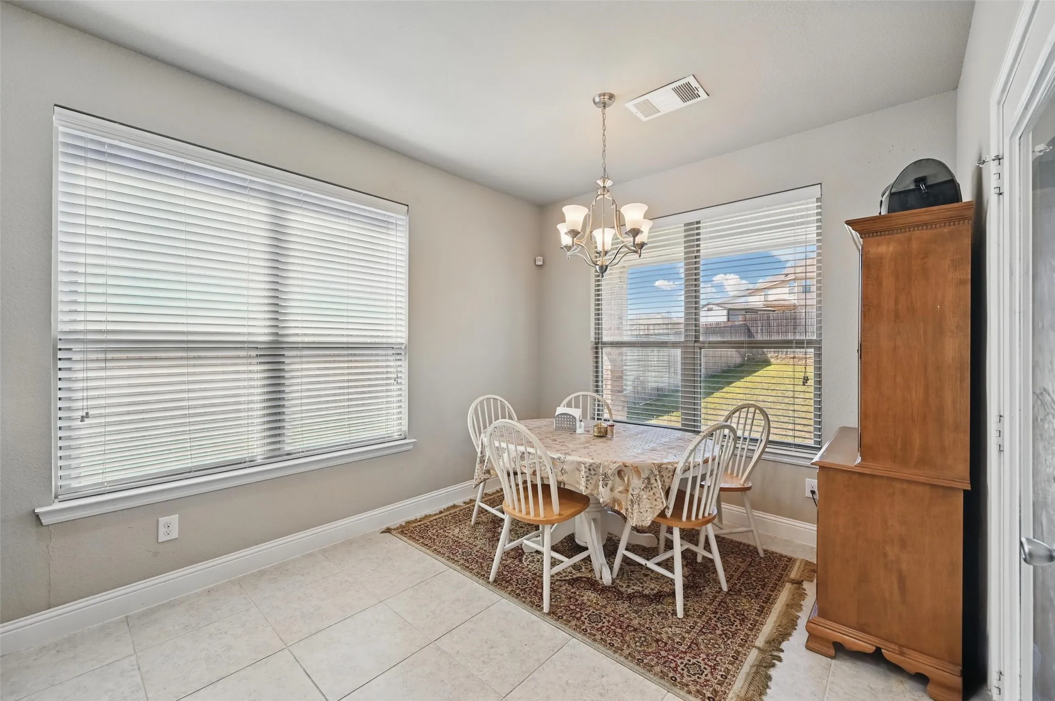 Tile flooring, multiple windows with blinds, and a chandelier lighting fixture