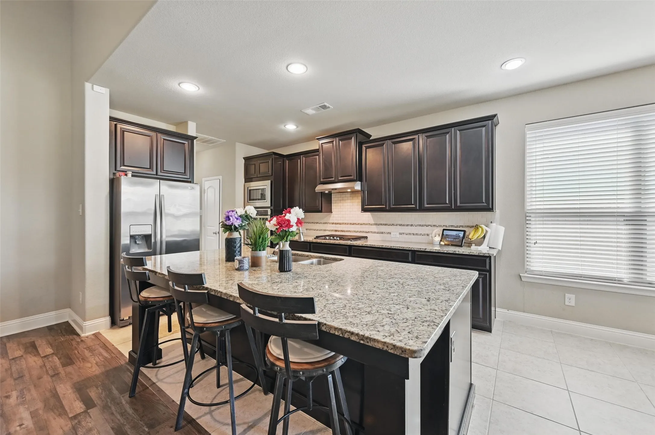 Kitchen featuring an expansive island with a stone countertop, dark wood cabinetry, stainless steel appliances, and recessed lighting
