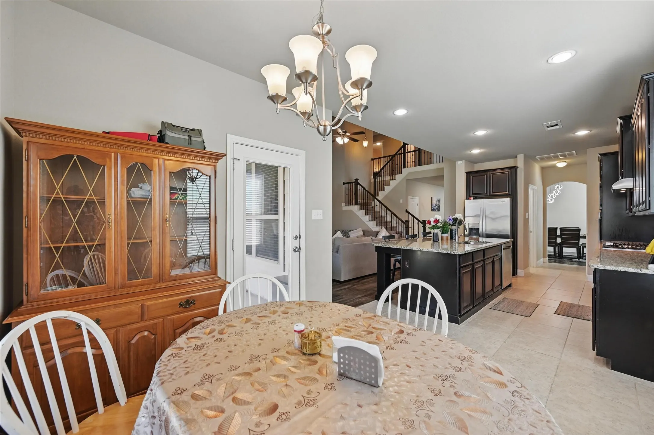 Kitchen featuring a central island with dark cabinetry, tile flooring, recessed lighting, and a stainless steel refrigerator