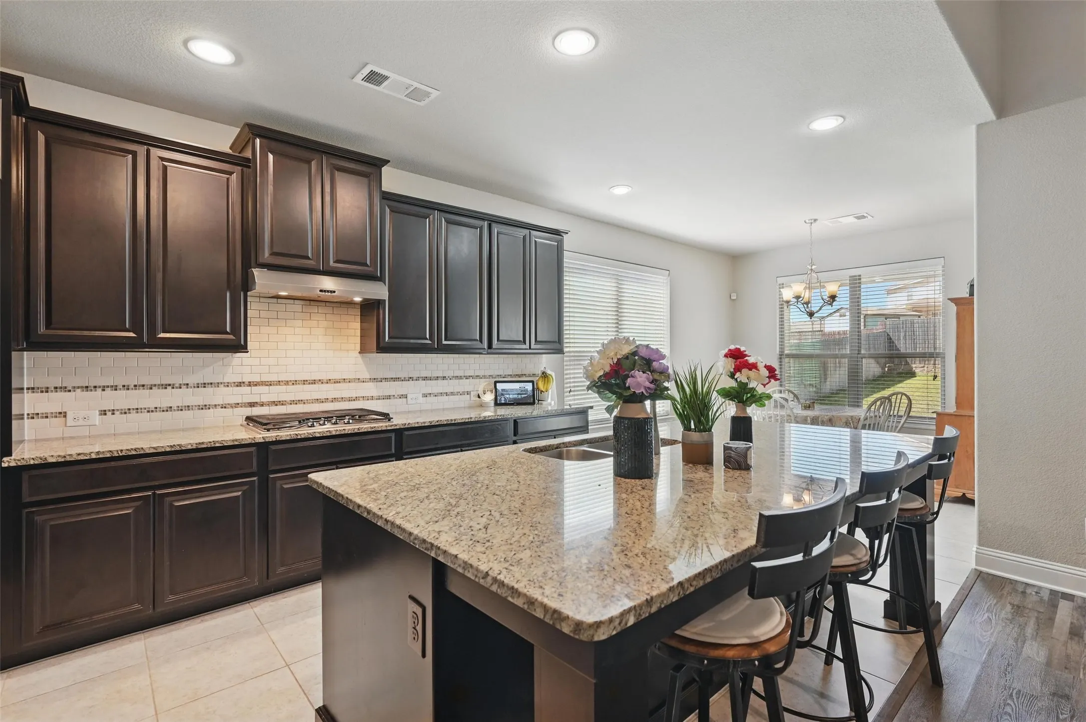 Kitchen featuring granite countertops, dark wood-finish cabinetry, tile backsplash, and recessed lighting
