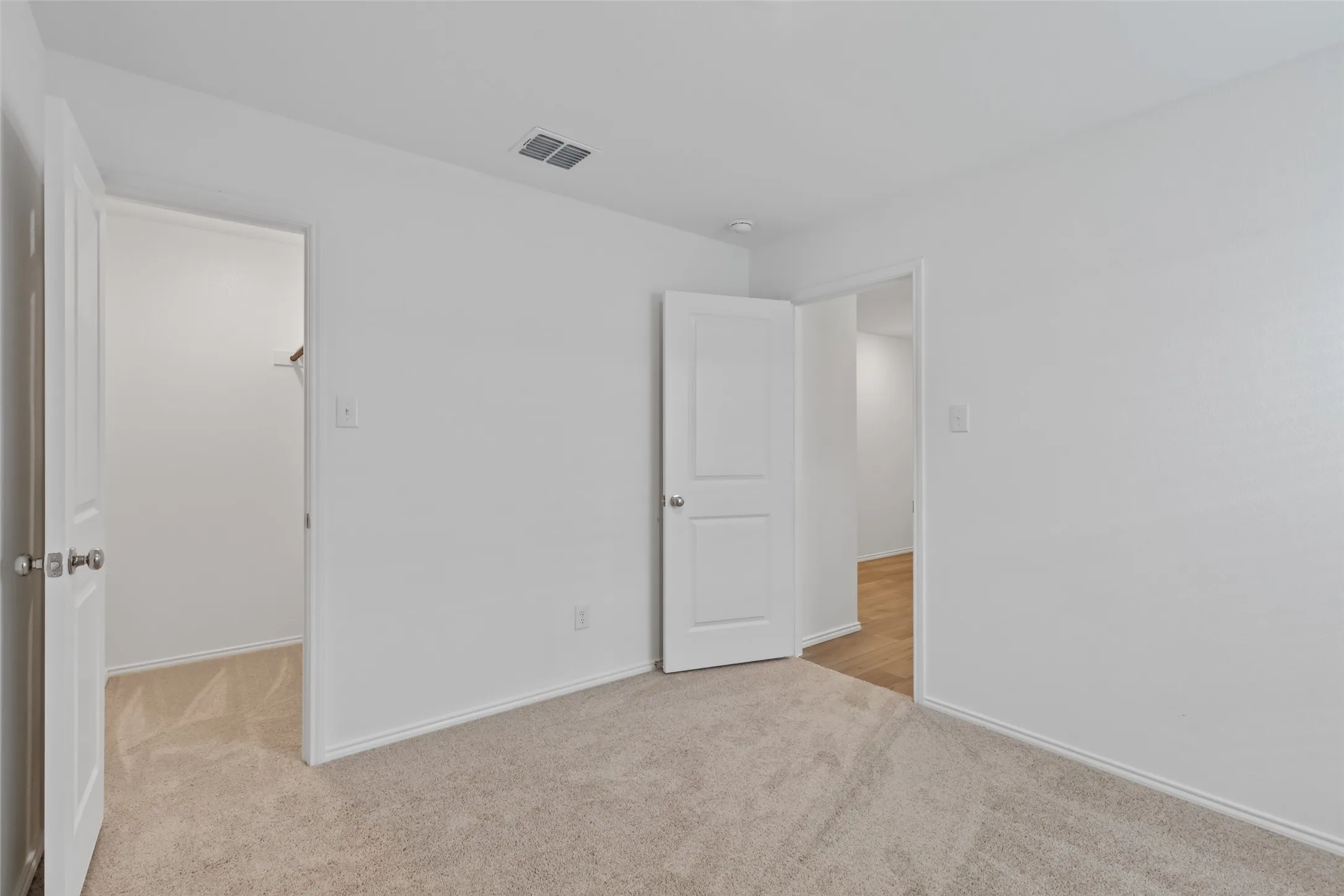 Wall-to-wall carpeting in a neutral tone, white painted walls, and white trim molding