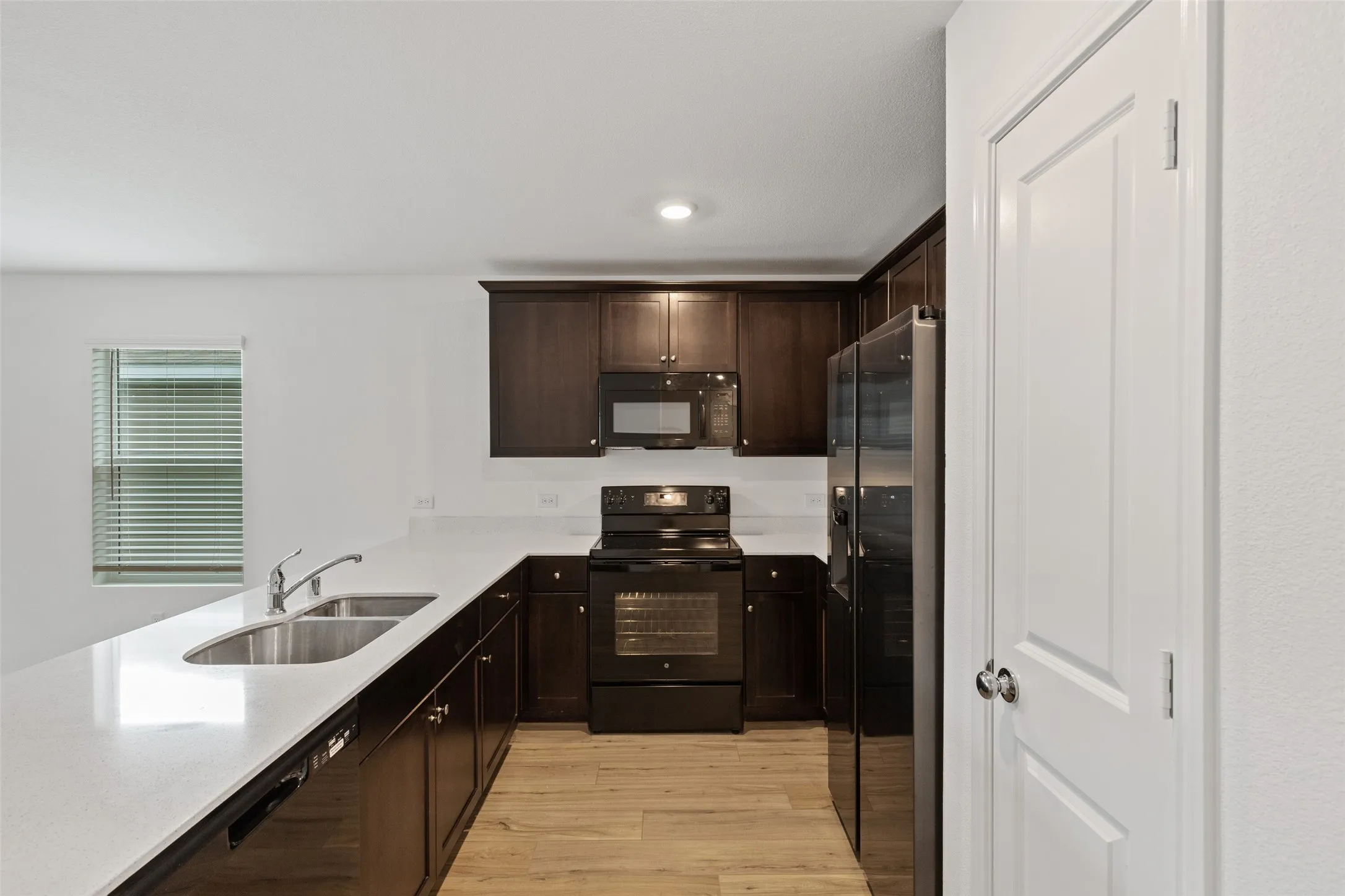 Kitchen featuring dark wood-finish cabinetry, light countertops, and wood-finish flooring