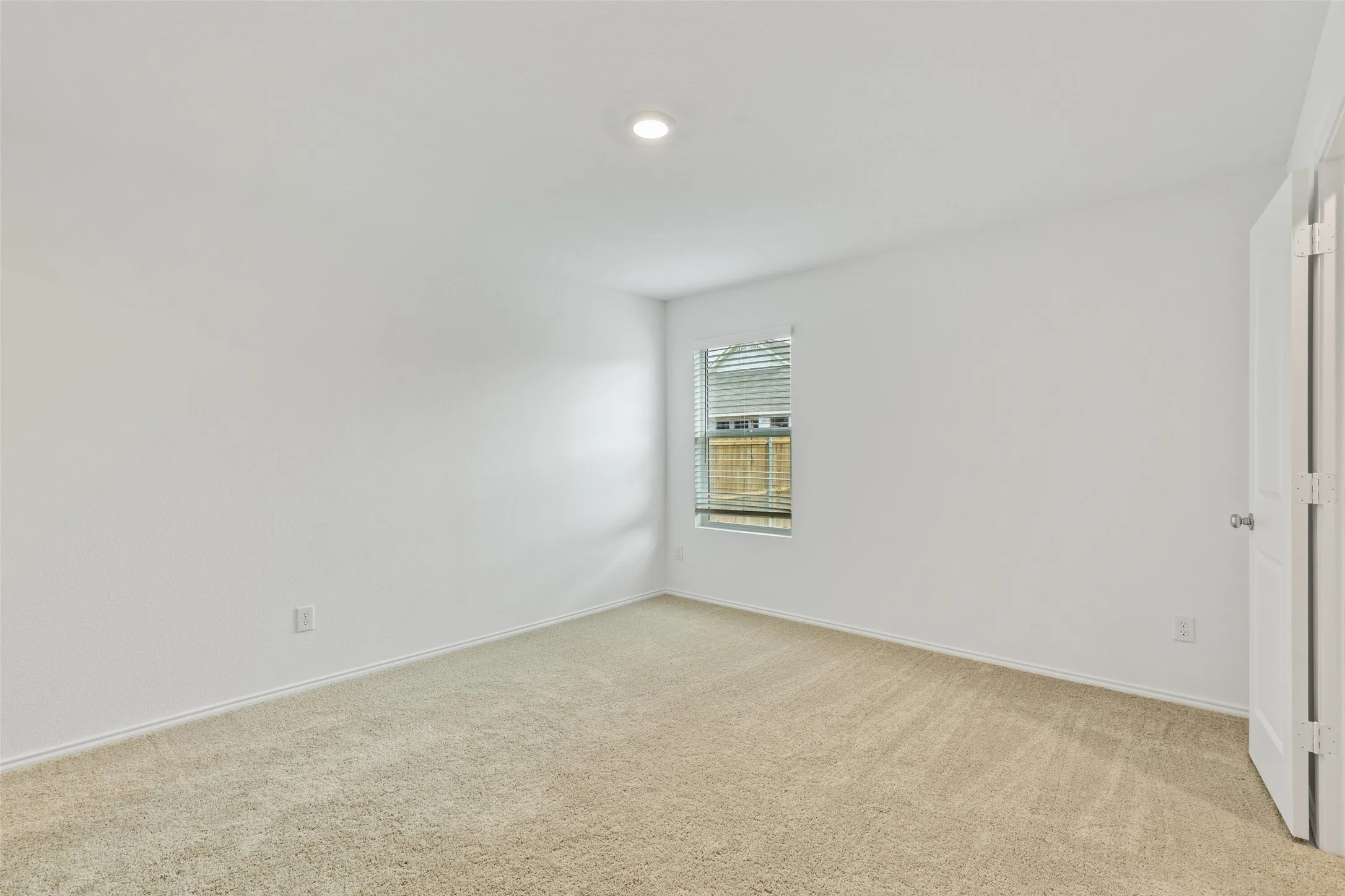 Window with horizontal blinds, neutral carpeting, recessed ceiling lighting, and a white paneled door
