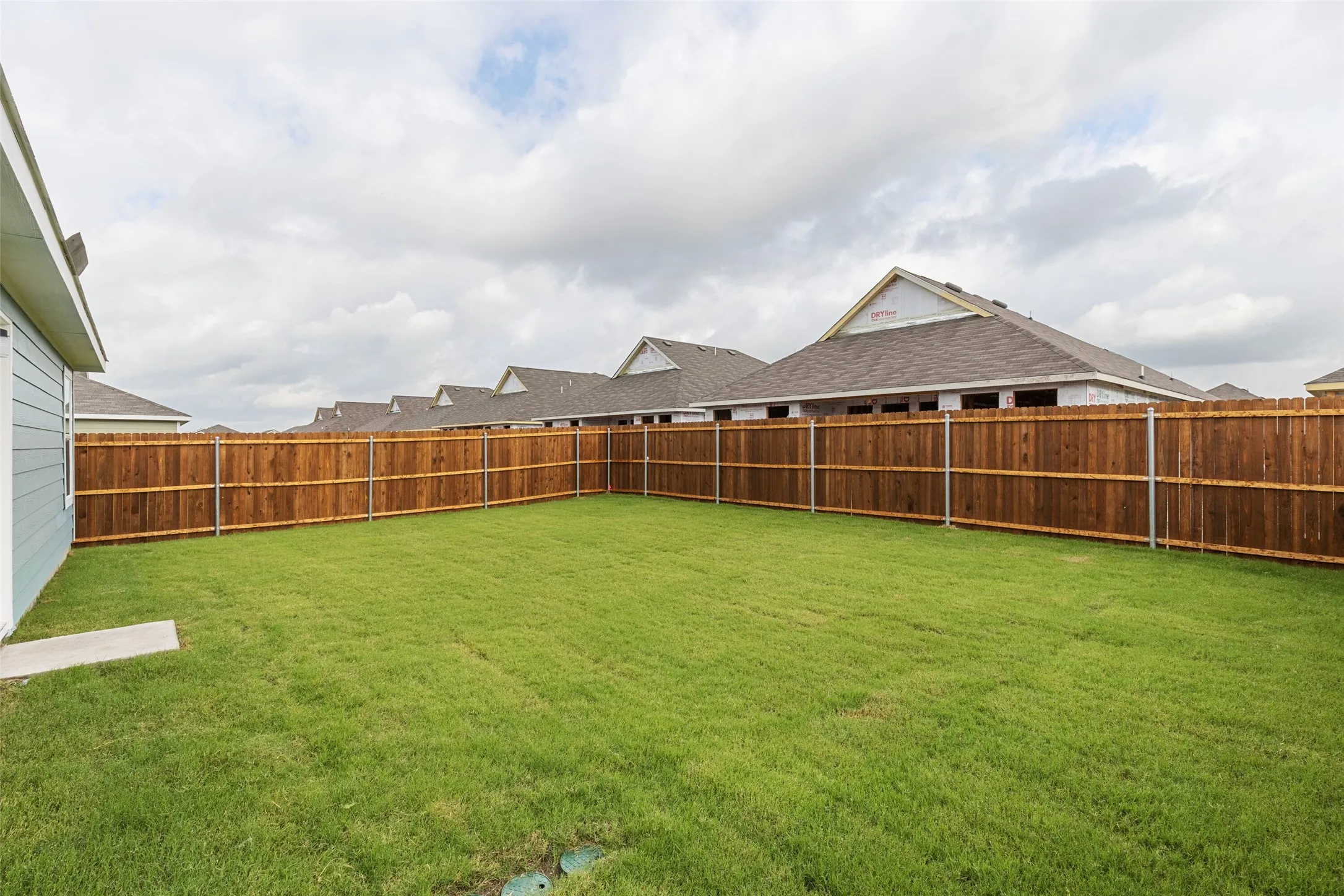 Expansive backyard featuring a manicured lawn and a privacy fence