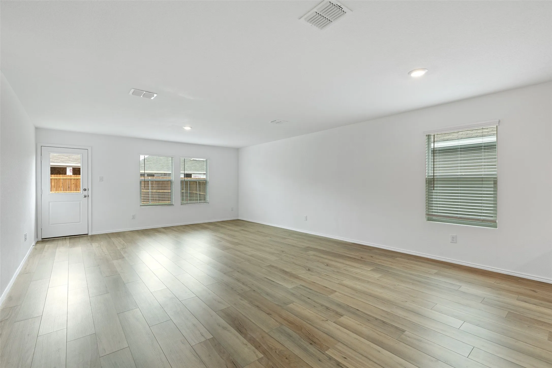 Expansive room featuring wood-finish flooring, recessed lighting, and multiple windows