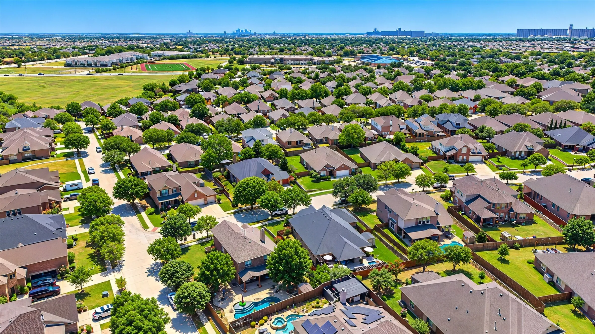 Aerial view house backyard on north (house is in the middle of two pools). Highland Middle School and football field. Downtown Fort Worth in the distance.