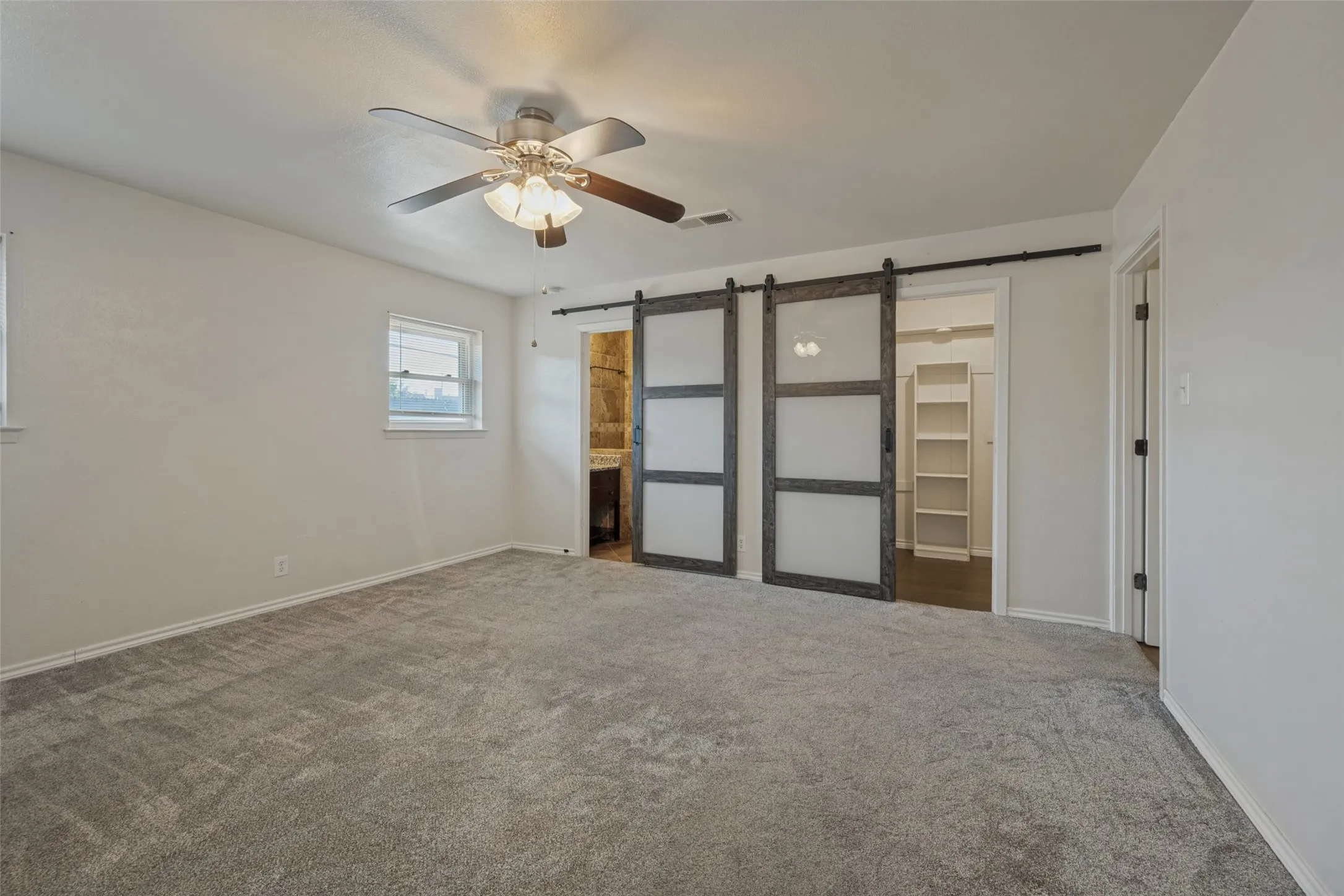 Spacious interior featuring a ceiling fan, light-toned walls, and soft grey carpeting